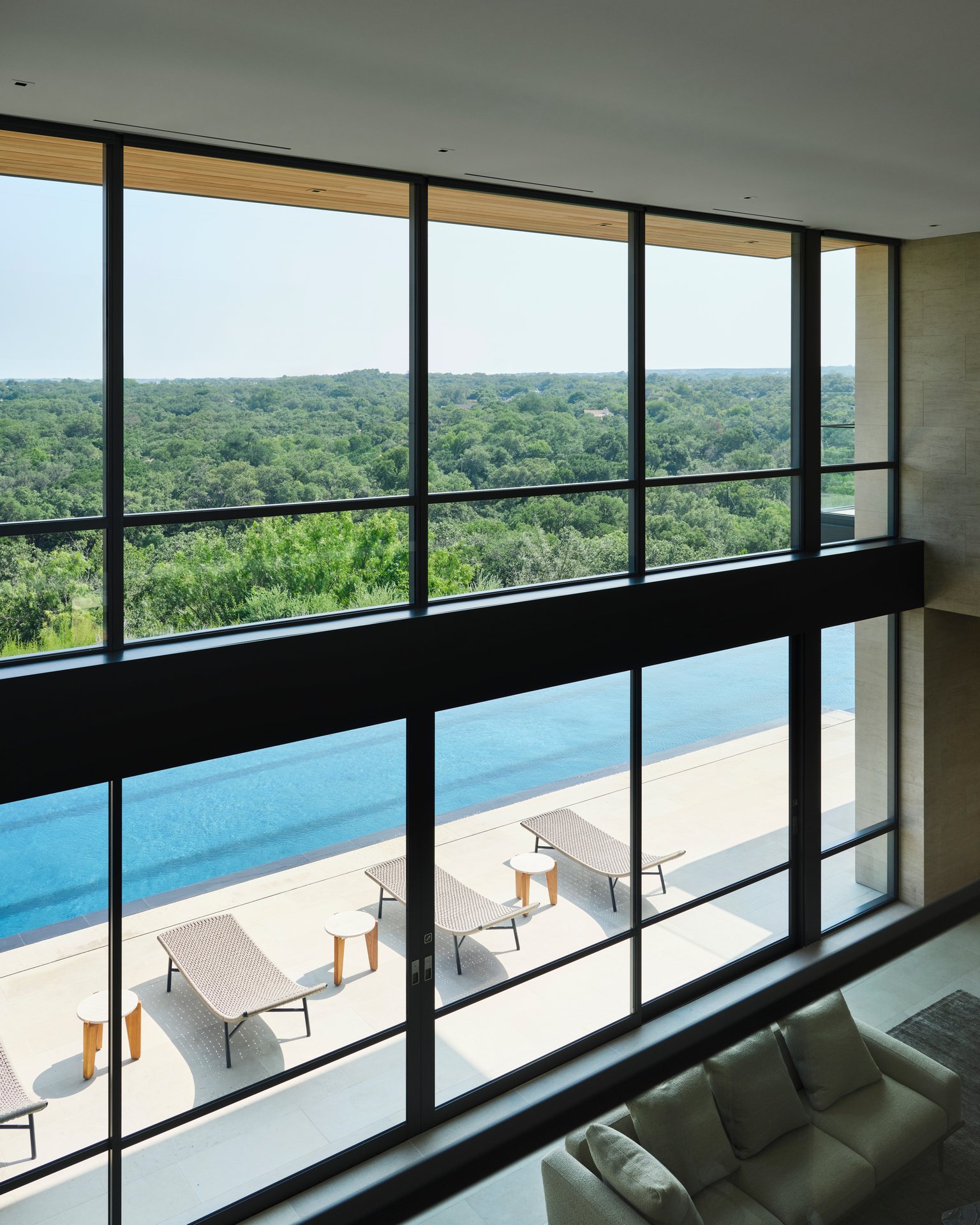 Large window wall framing expansive views across the swimming pool and surrounding landscape. Clean architectural lines emphasize openness and natural light.