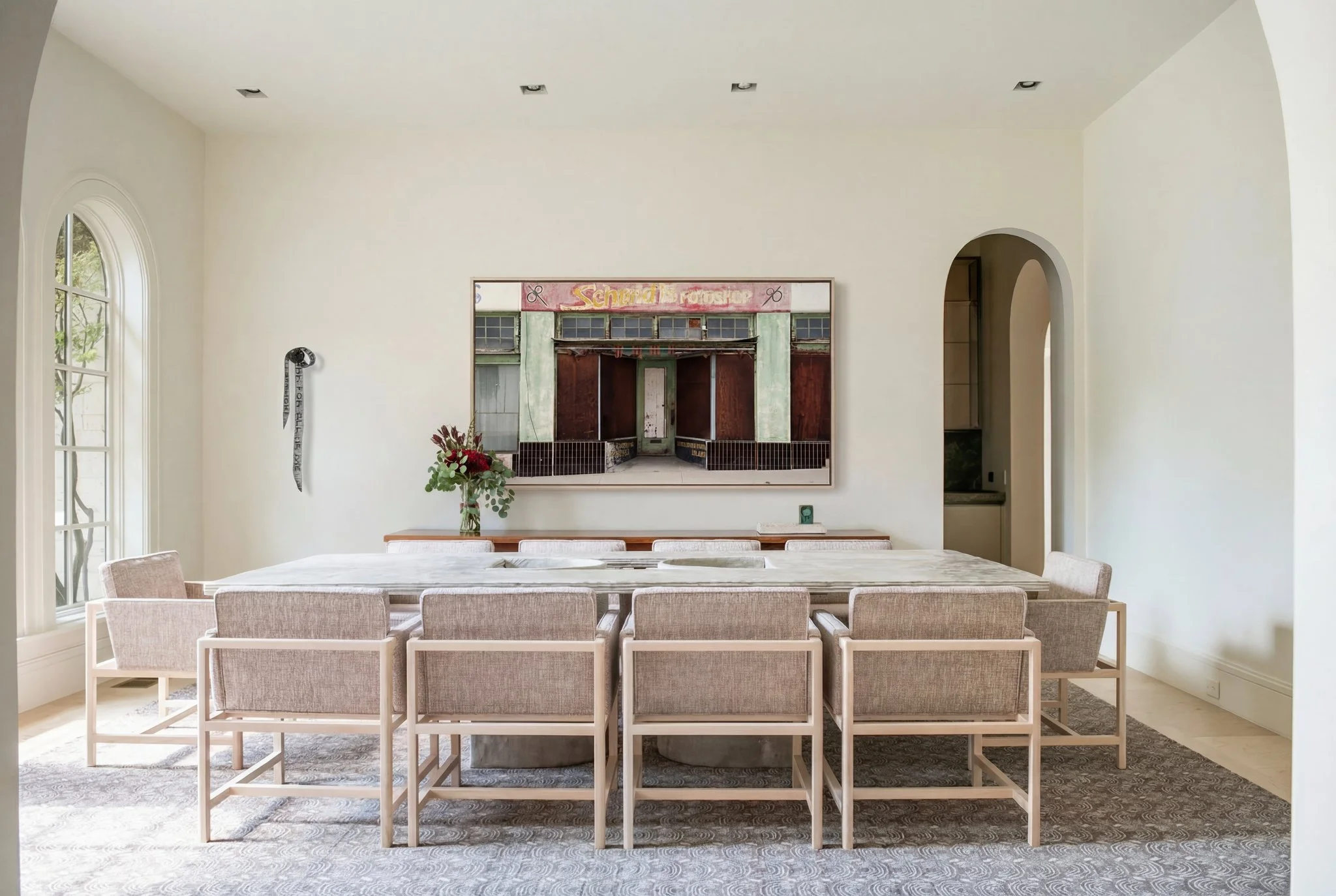 Formal dining room with large sculptural concrete dining table, upholstered chairs by Bassam Fellows, contemporary art by Al Oliver and Linda Ridgway and soft architectural light in a luxury Dallas home.