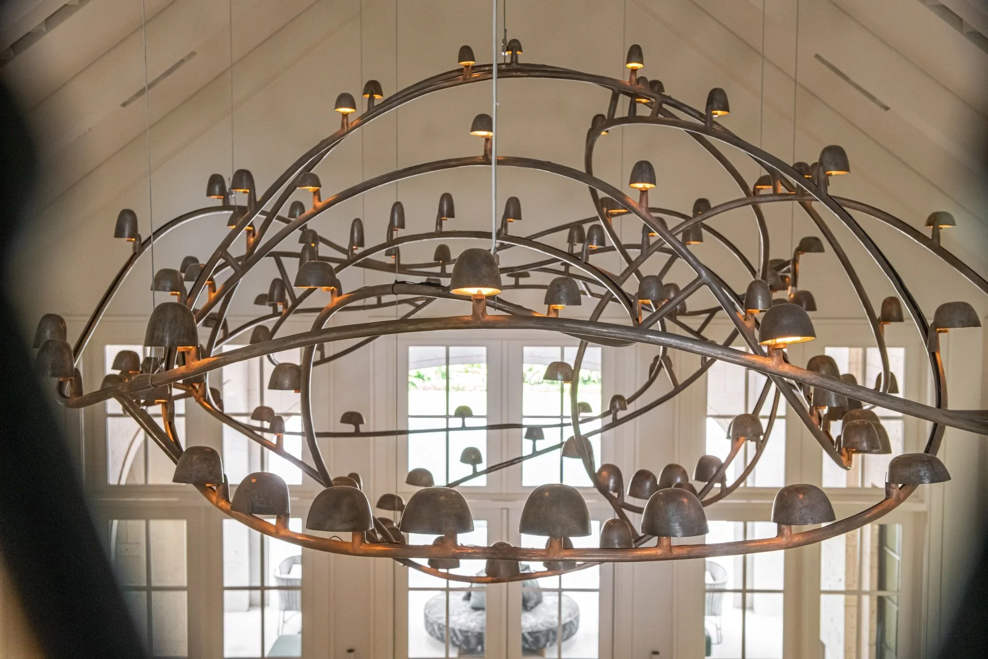 Statement bronze chandelier by Frederik Molenschot suspended in a vaulted ceiling, creating architectural drama and warm ambient light in the main salon.