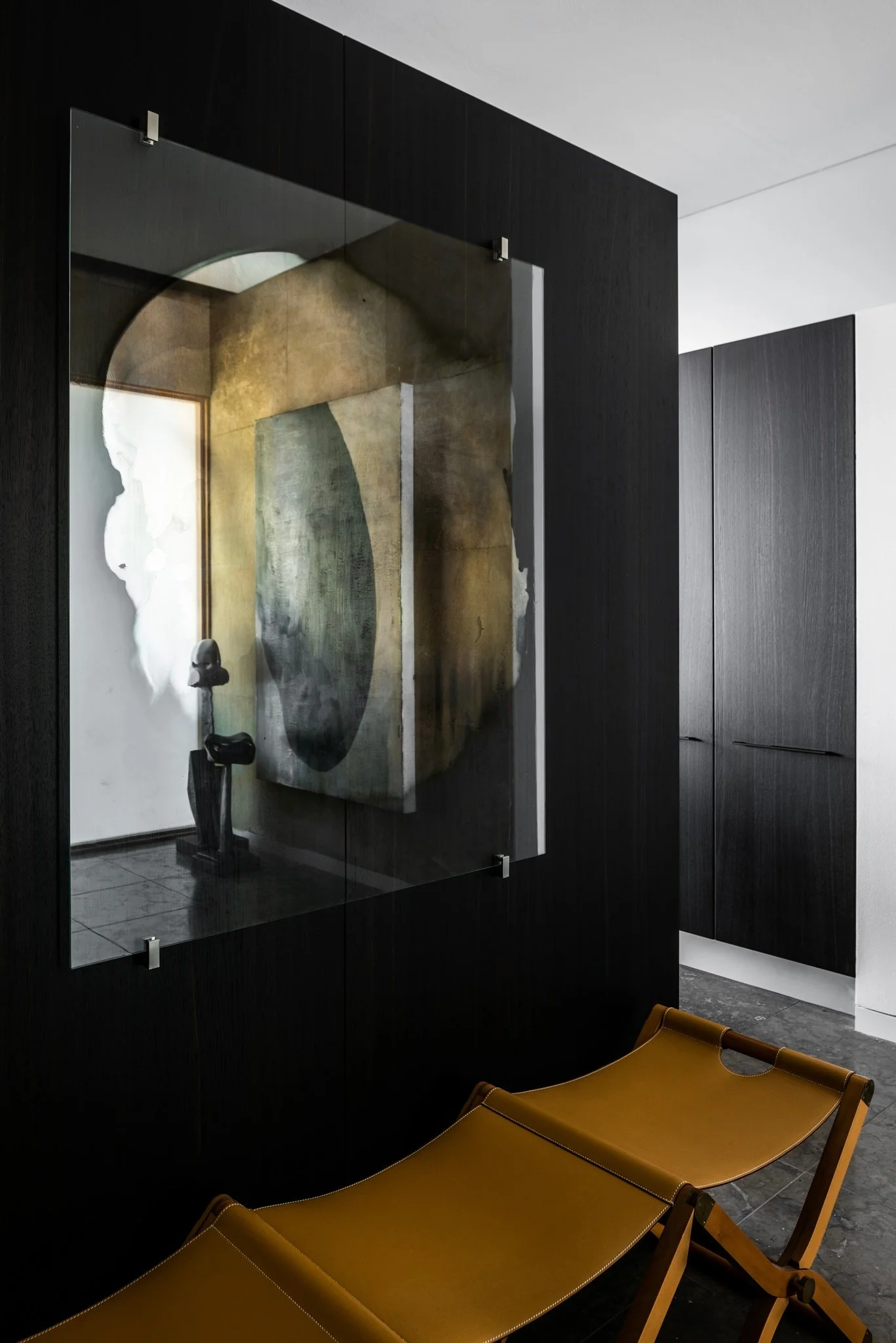 Contemporary artwork mounted on glass panel over dark wood wall with sculptural seating in modern luxury interior.  antonio murado hermes pippa jenny Nordberg