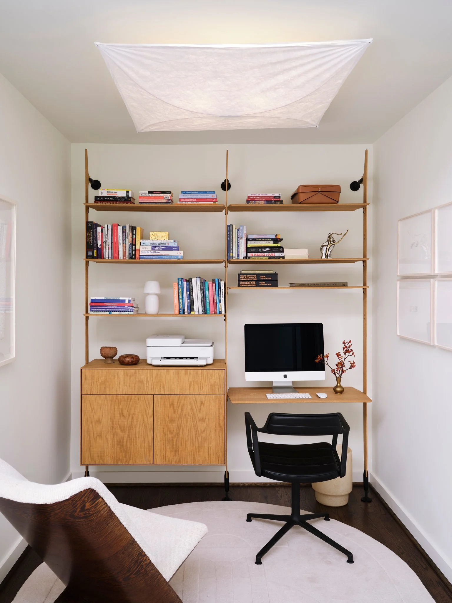 Modern home office with wood shelving system by Jader Almeida, integrated desk, and curated books, defined by clean lines and functional interior architecture. Ceiling fixture from Tobia Scarpa.