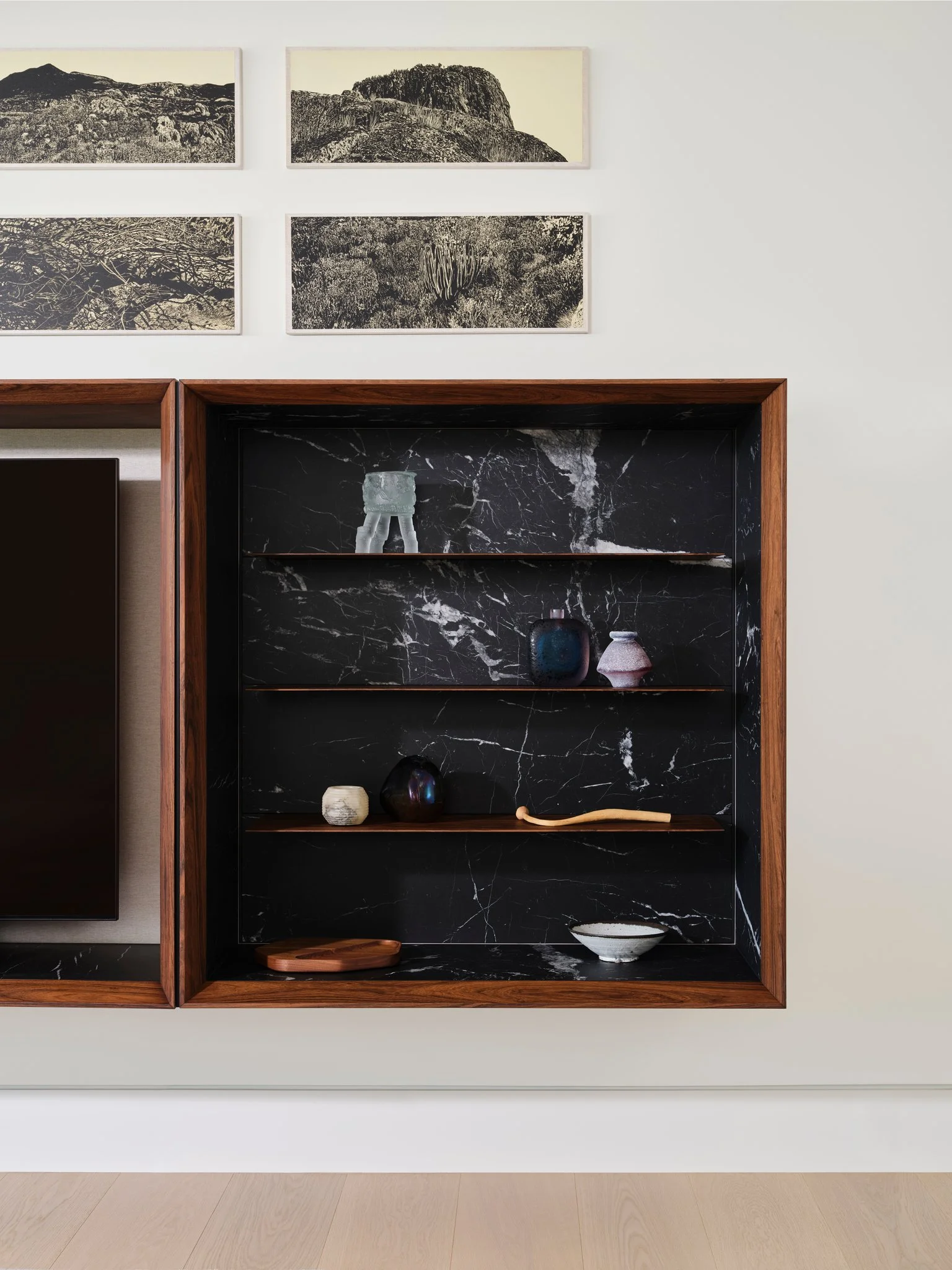 Custom walnut cabinet by Jader Aleida with dramatic black marble interior showcasing ceramics and collectible objects. A refined display piece integrated into a contemporary residential interior.