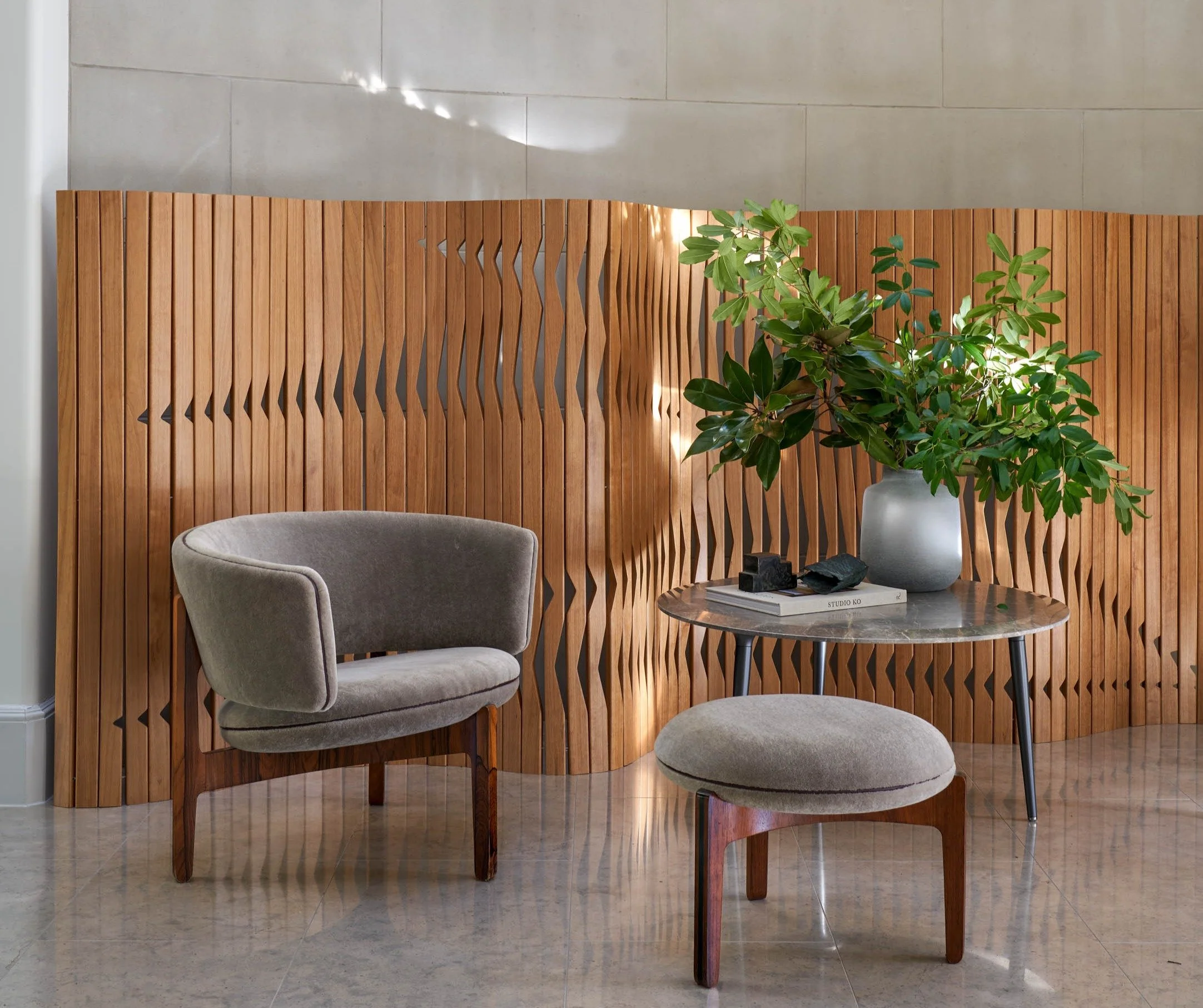 Danish Modern lounge chair vignette with sculptural wood slat wall, marble side table, and indoor greenery danish design