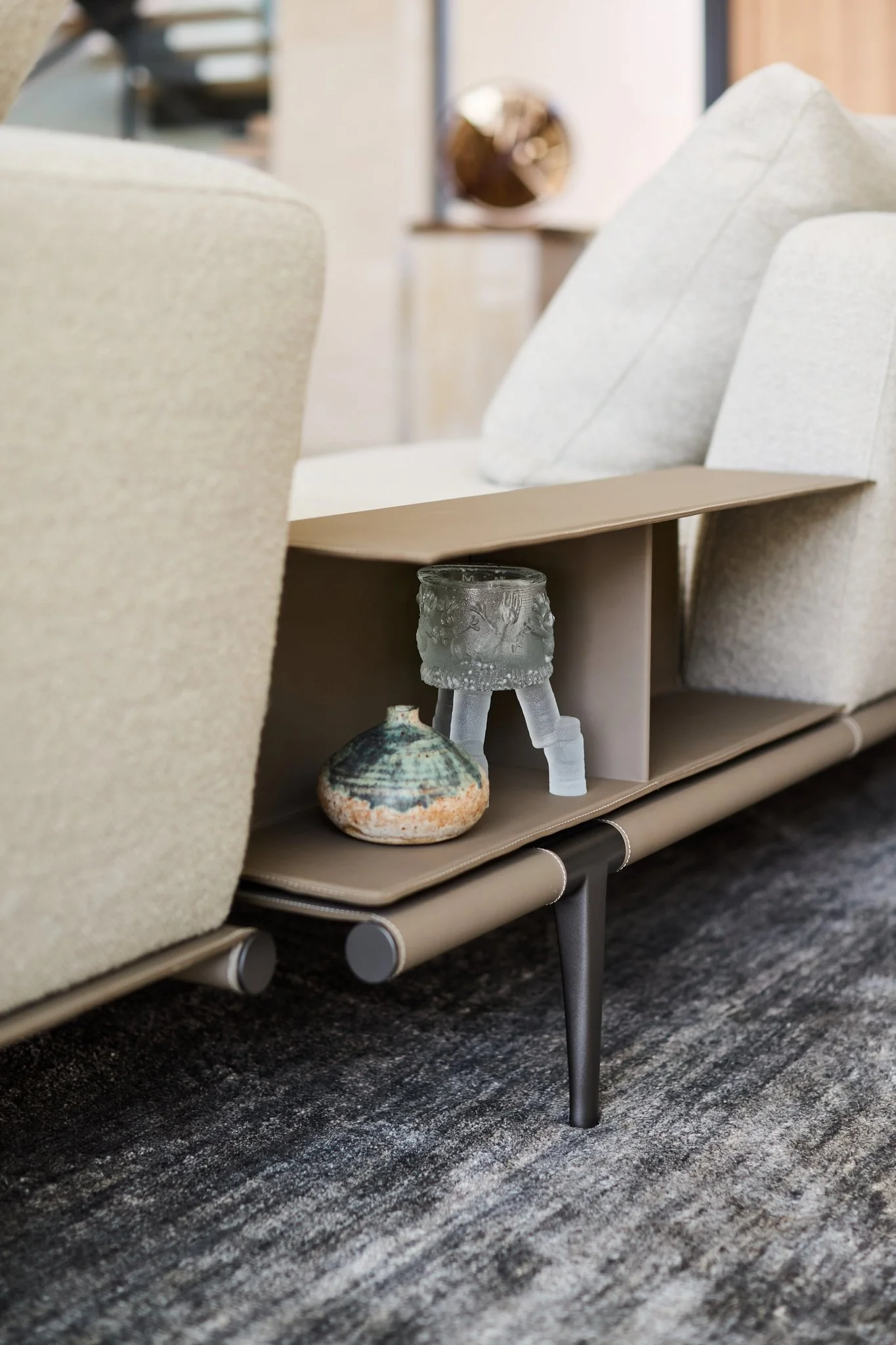 Custom sofa console shelf with curated ceramic and glass objects in modern luxury living room. Poltrona Frau, Mohair rug