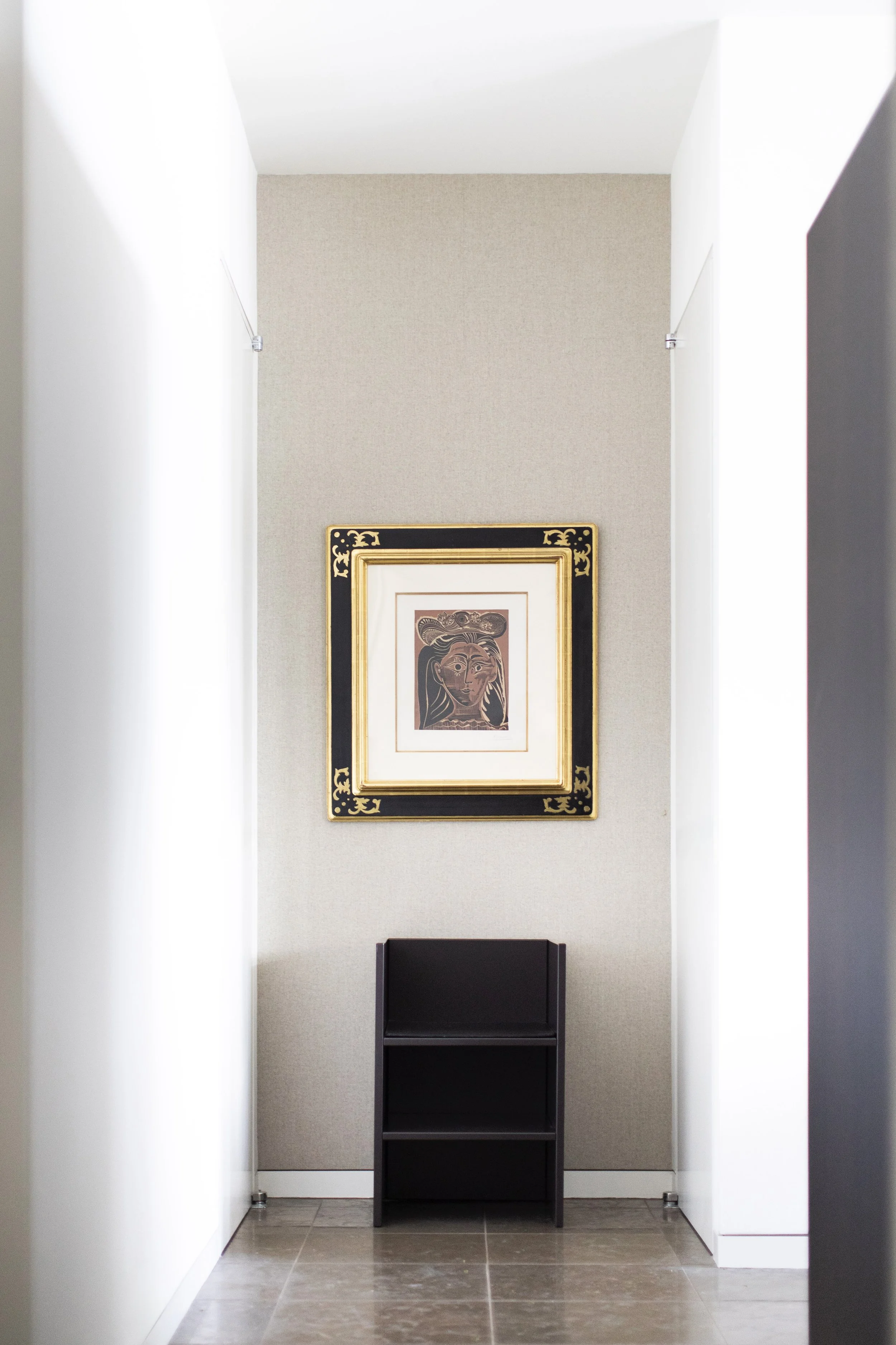 Luxury modern hallway niche with framed abstract artwork and minimalist black pedestal shelving.  Donald Judd Pablo Picasso