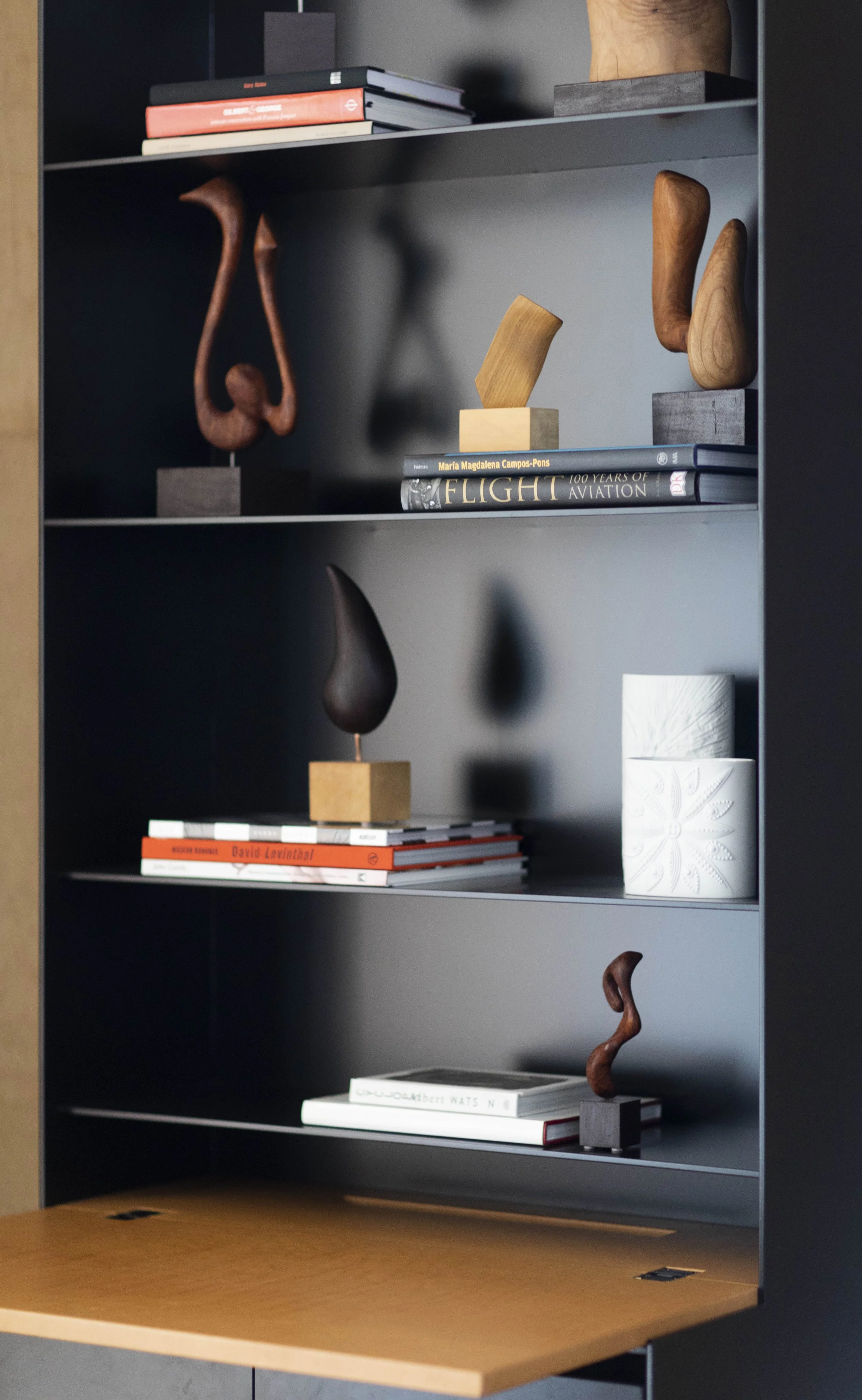 Custom shelving with collectible wooden sculptures, design books, and curated objects in modern luxury interior.  jonathan nesci cabinet, japanese sculptor Teruo Kinoshita