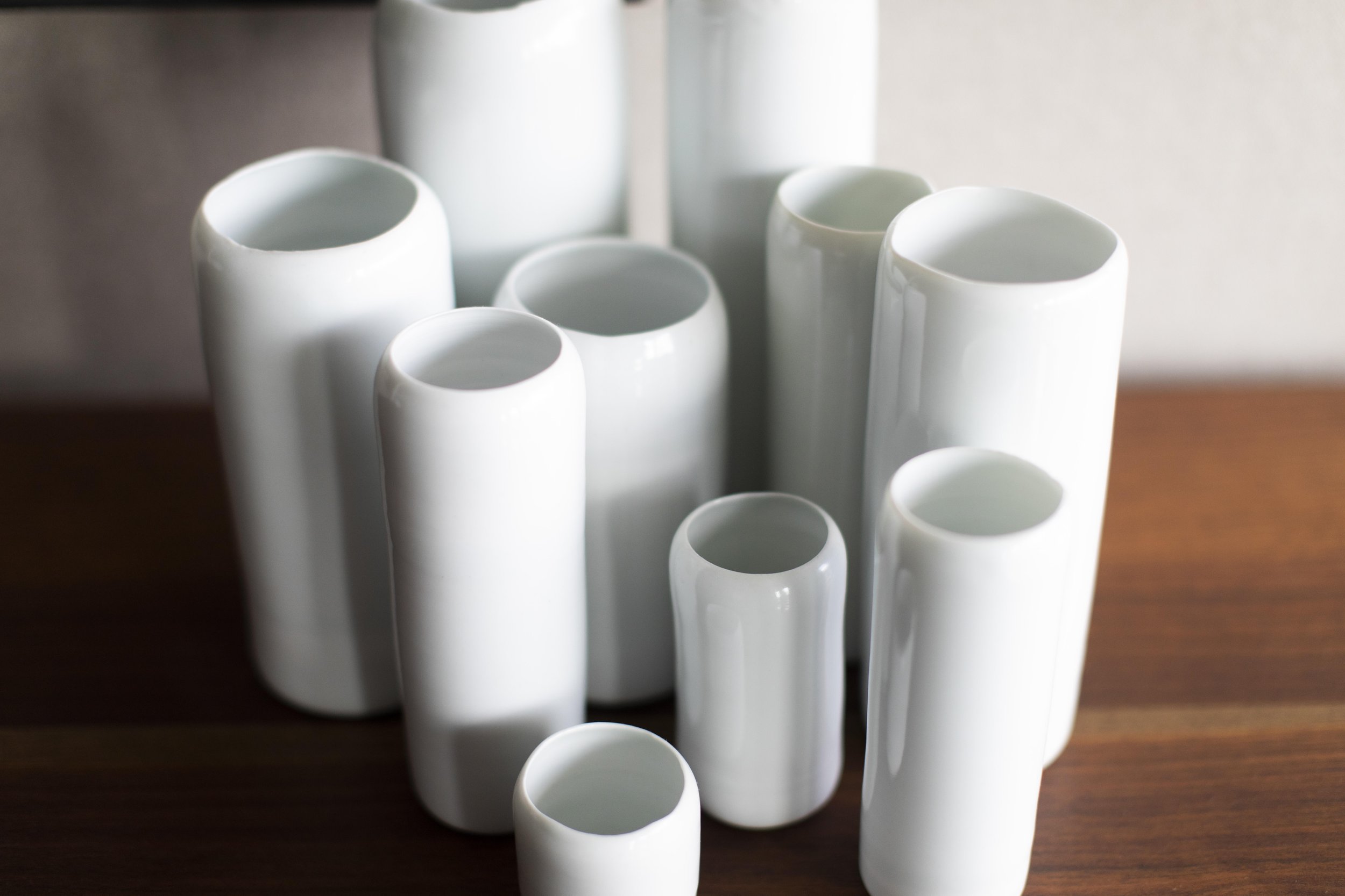 Minimal white porcelain ceramic vessels displayed on wood surface in modern luxury interior styling lilith rockett