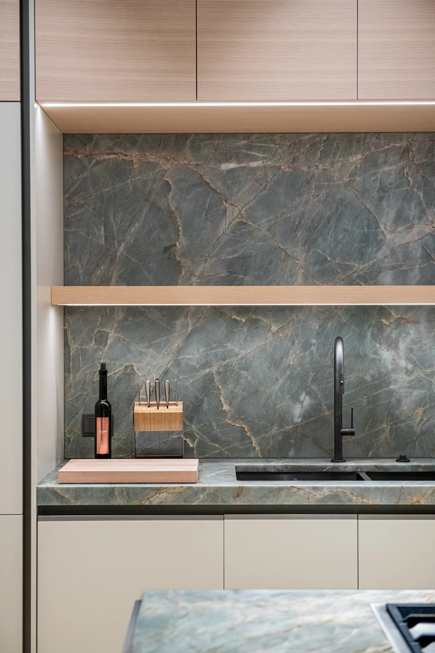 A substantial stone island anchors the kitchen, framed by warm oak cabinetry and softly arched passages. Integrated appliances and restrained detailing allow proportion and material to lead the design.