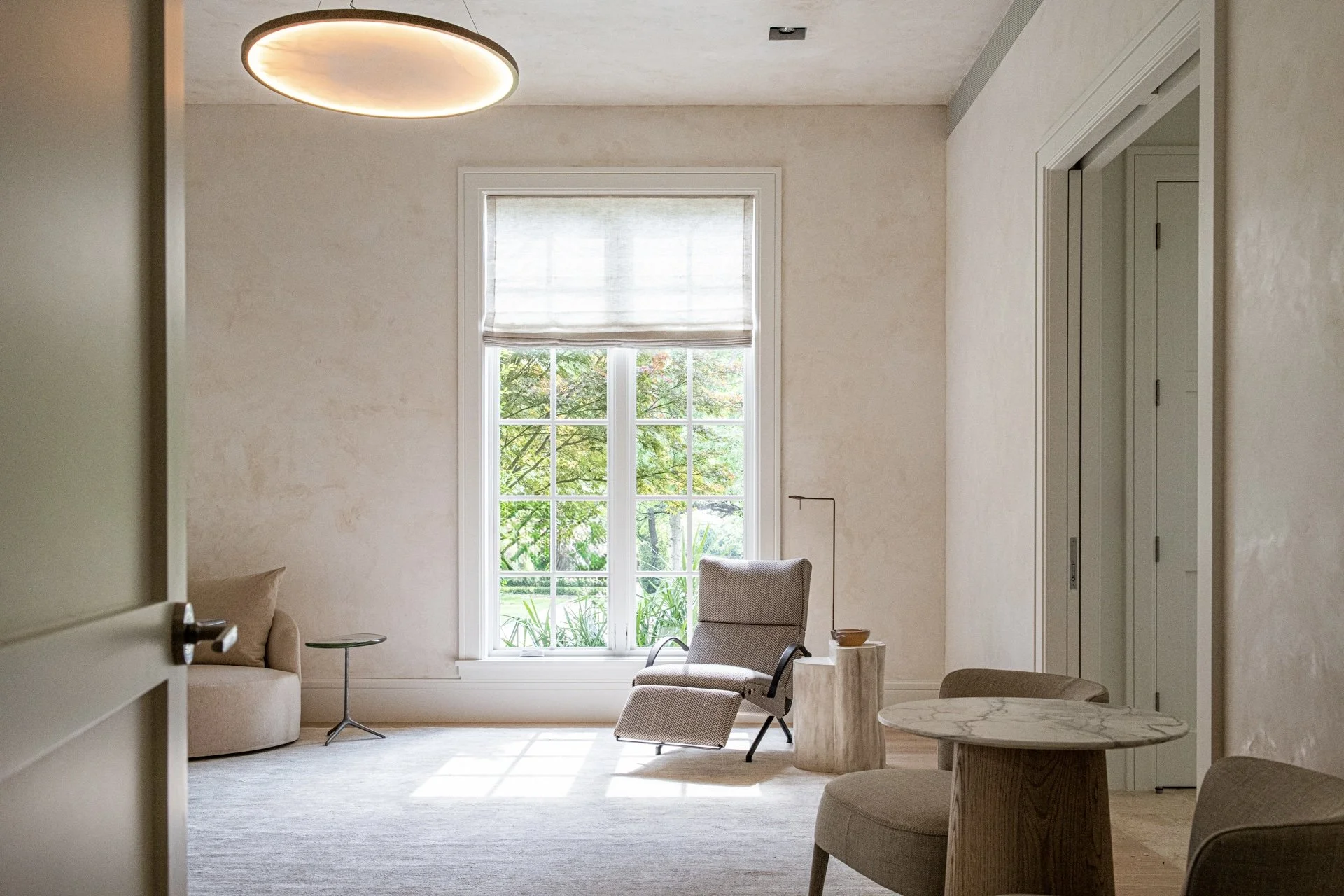 Quiet minimal office with sculptural lounge seating, soft plaster walls, natural light, and restrained contemporary luxury interior design.