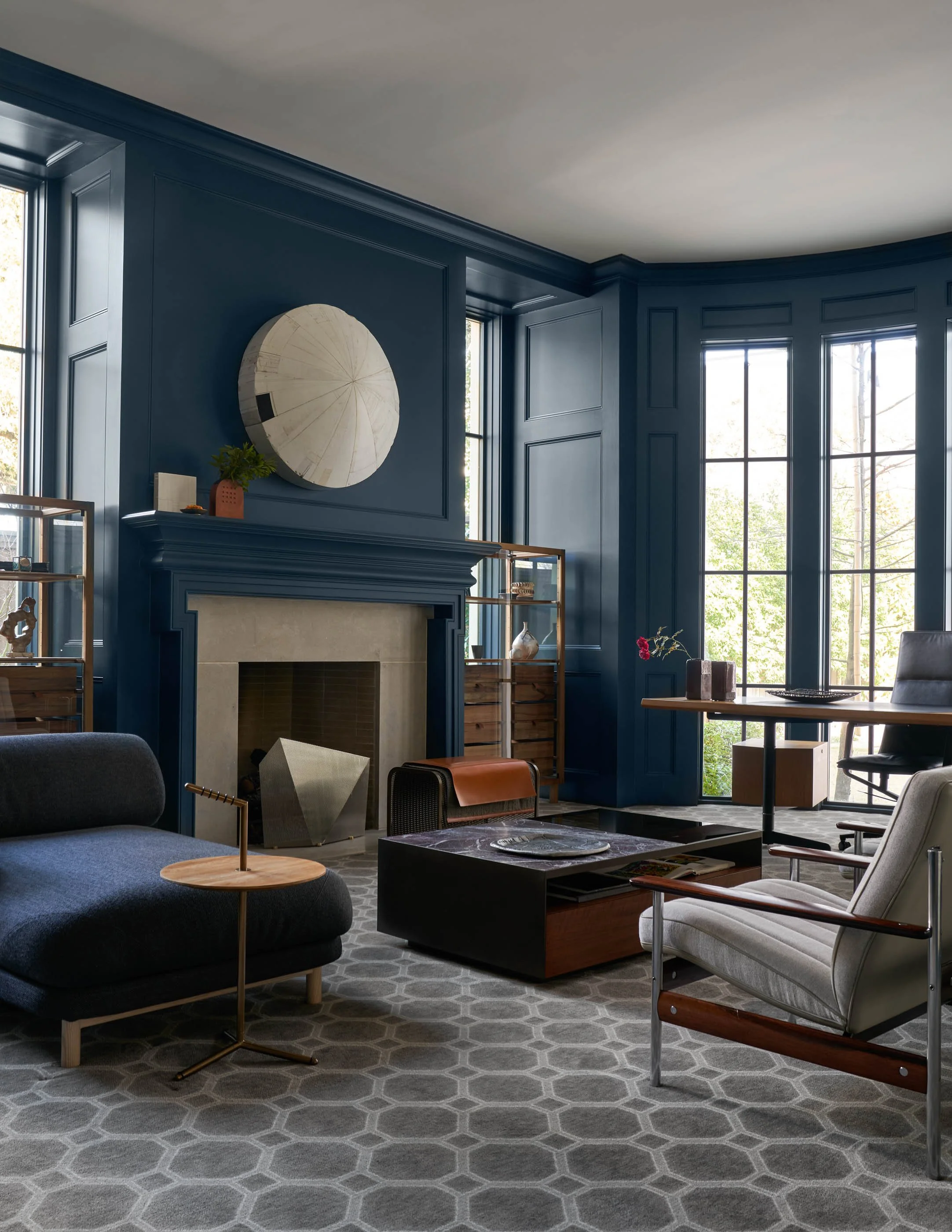Moody modern study with deep blue paneled walls, stone fireplace, and curated contemporary furniture hiroyuki hamada