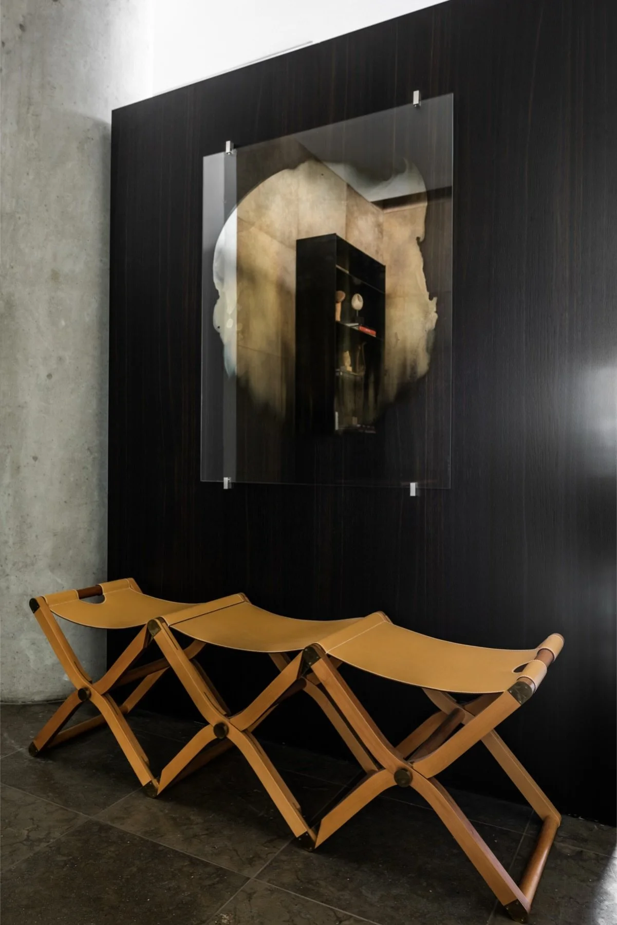 Contemporary artwork mounted on glass panel over dark wood wall with sculptural seating in modern luxury interior.  antonio murado hermes pippa jenny nordberg jonathan Nesci