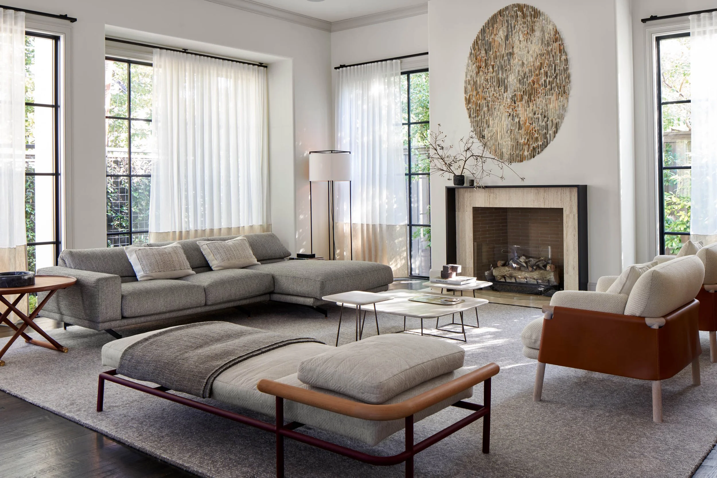 Luxury modern living room with sectional sofa, stone fireplace, and large contemporary wall sculpture by jessica drenk