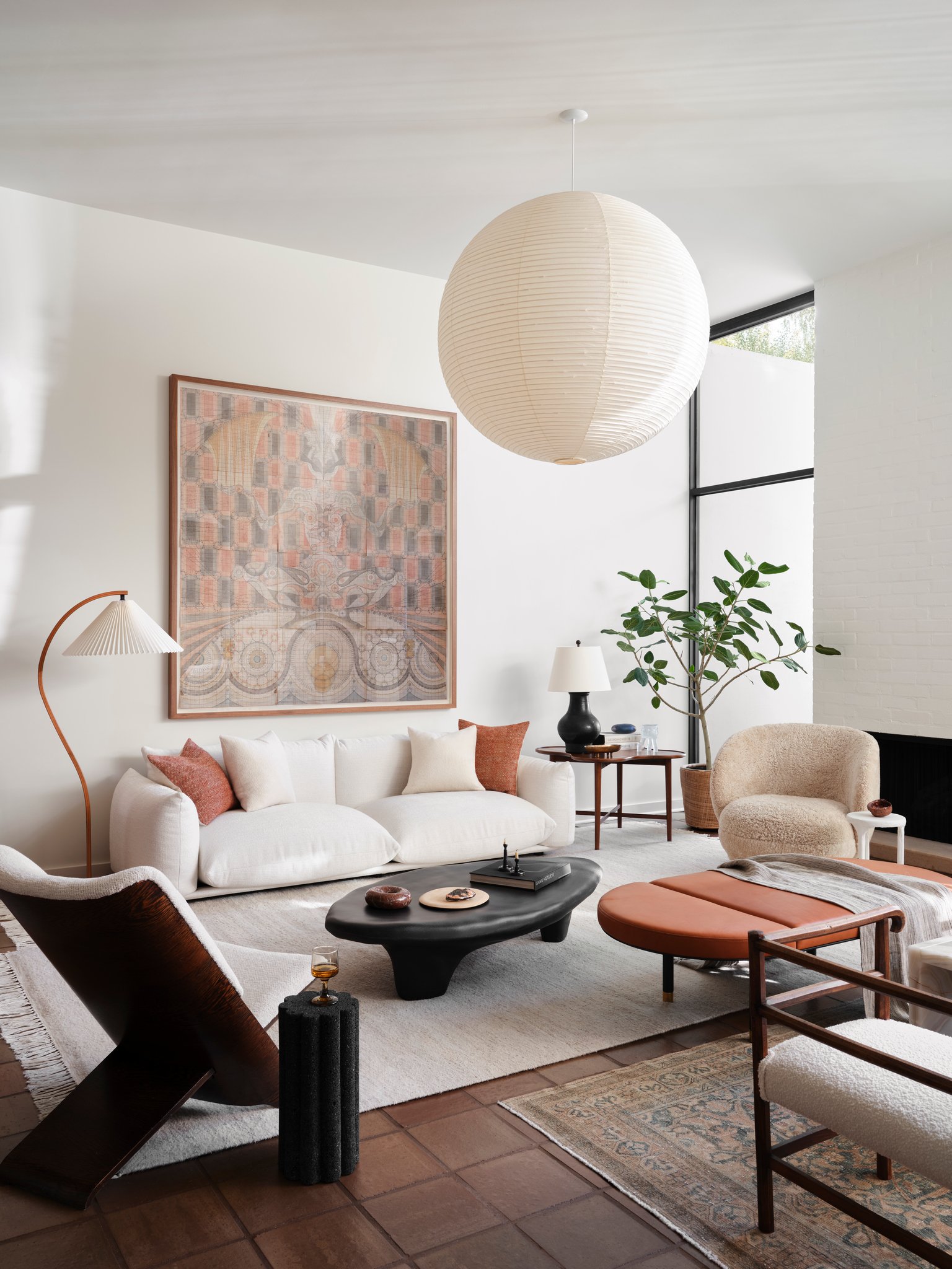 Modern living room with low-profile Marenco Sofa, design Mario Marenco., Noguchi Paper Lamp, large-scale artwork, and sculptural fiberglass coffee table, defined by soft textures and warm neutral tones.   Chair by Theo Ruth in the Foreground.