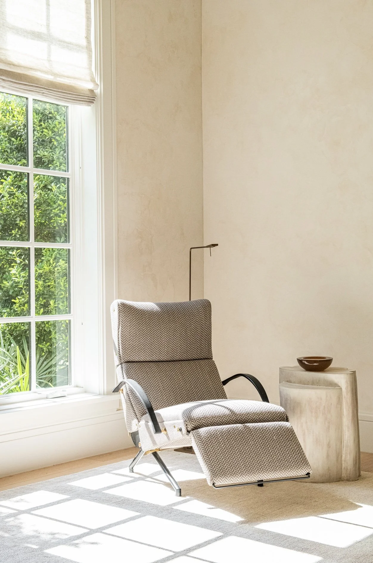 A serene reading corner centered around a rare vintage lounge chair by osvaldo borsani and ceramic pedestal. Natural light, soft plaster walls, and restrained styling create a calm and timeless retreat.