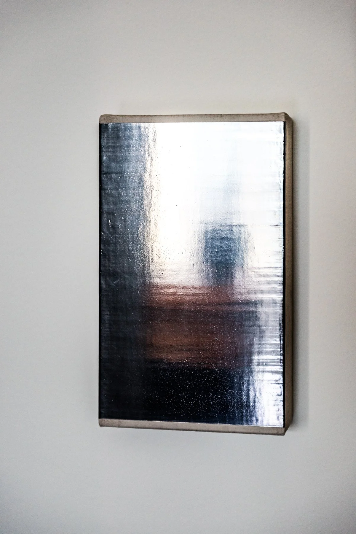 Abstract contemporary artwork with reflective surface mounted on white wall in modern interior polished graphite on linen Mathew Allen artist