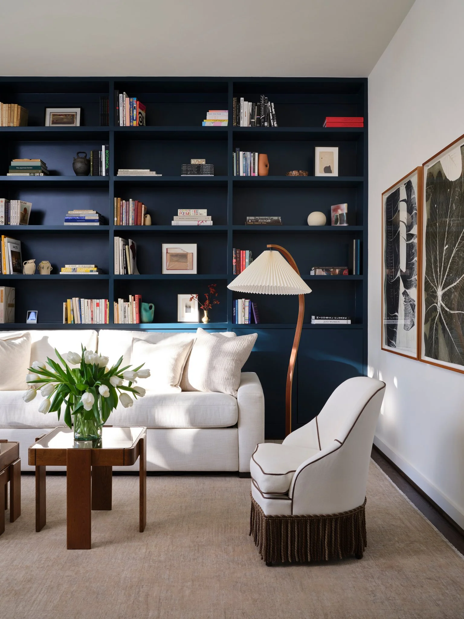 Contemporary living room with deep blue built-in shelving, neutral sofa, and sculptural lighting, balancing color, texture, and architectural order.