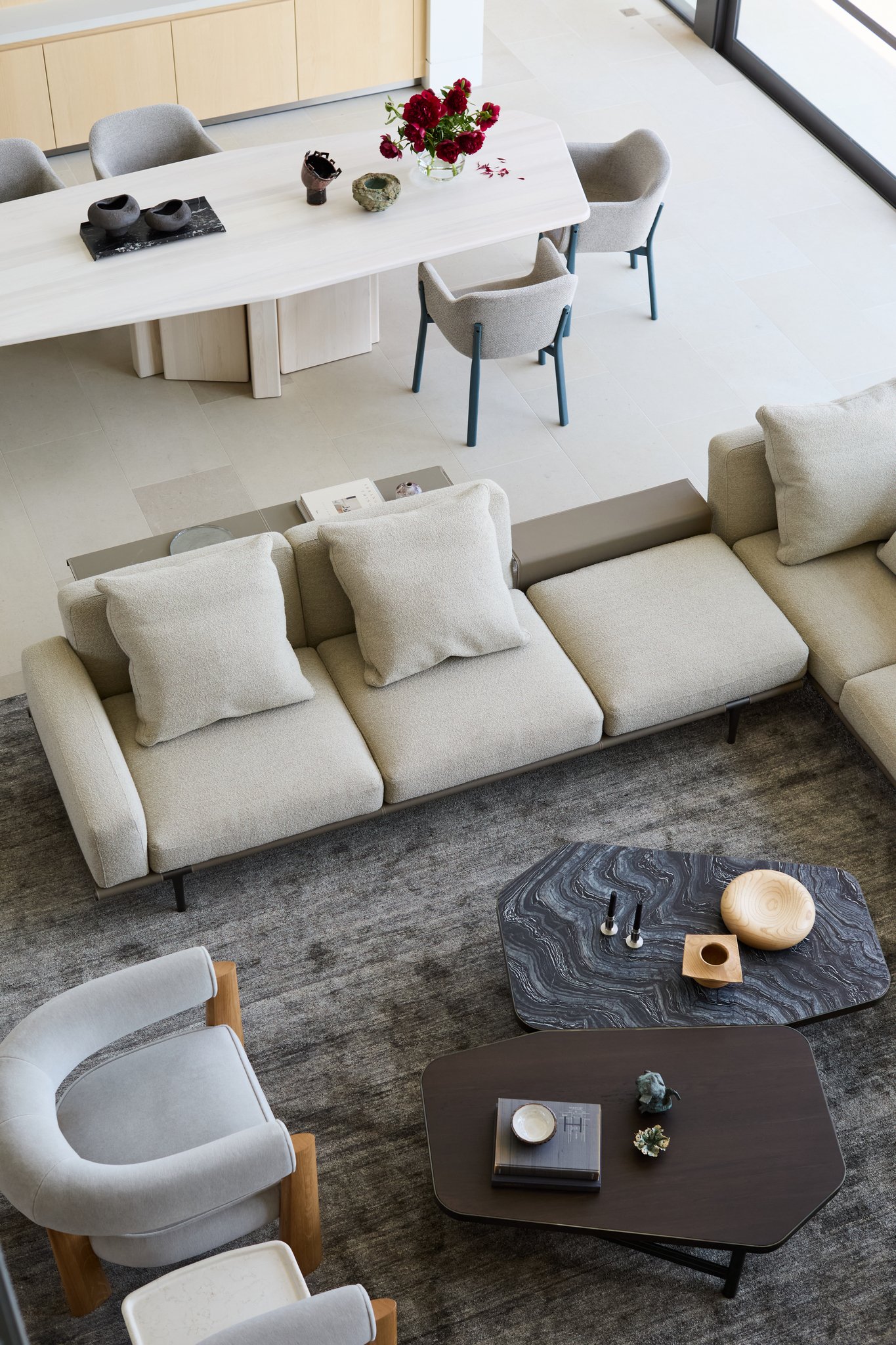 Contemporary living room with sculptural coffee tables, modular sofa, and textured area rug in luxury modern home. Henge tables, poltrona frau sofa, simon johns table rische collection bishop table, bulthaup kitchen