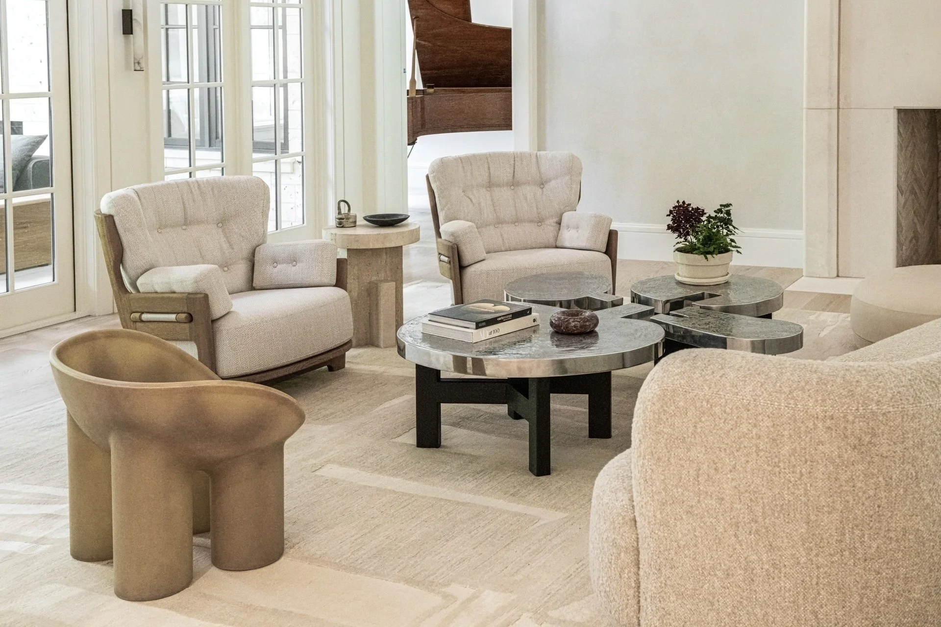 Collected living room with sculptural seating by Faye Toogood and guillerme et chambron, metal cocktail tables by Ado Chale, soft neutral textiles, and refined architectural warmth.