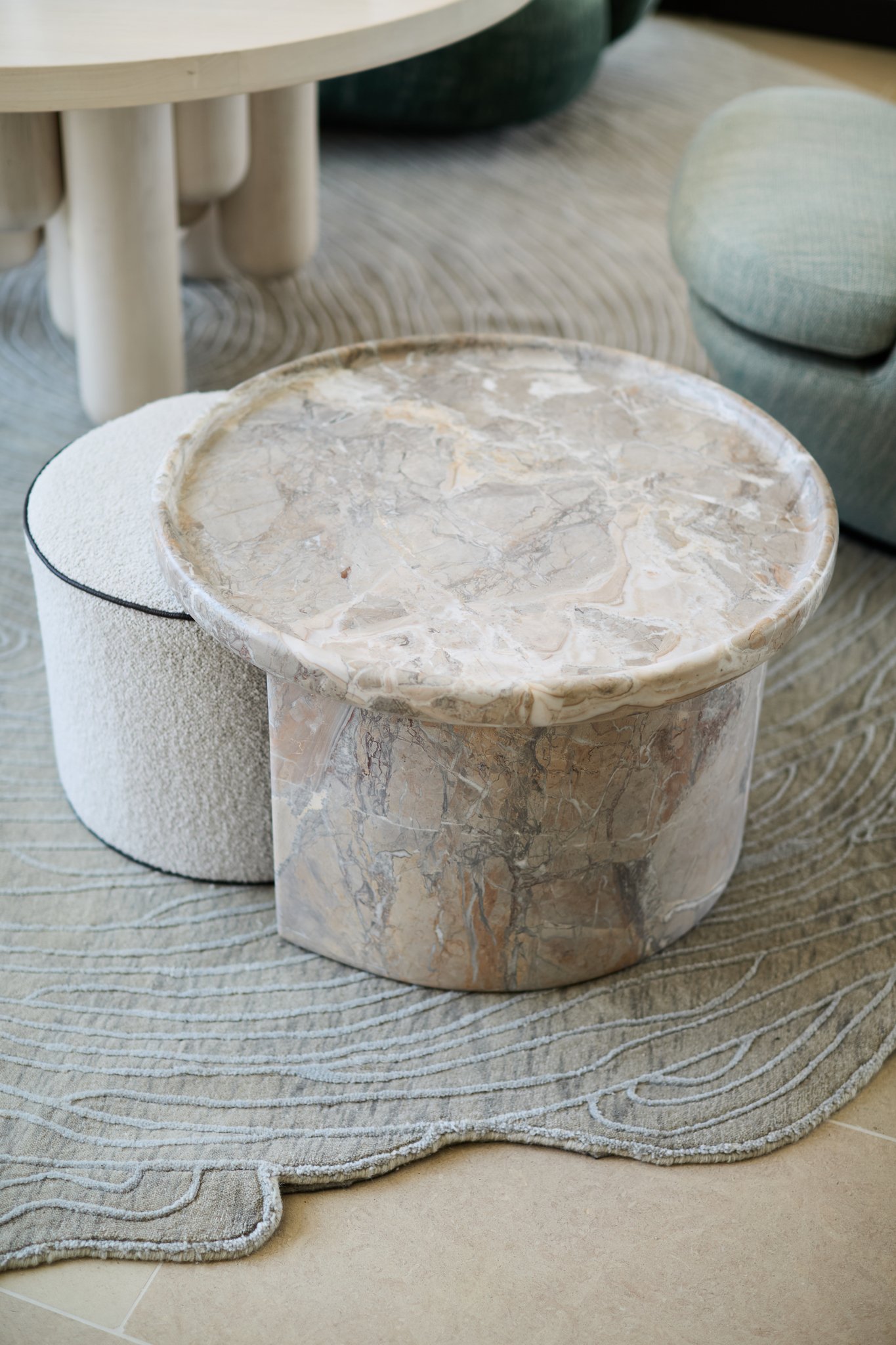 rische collection seren table on atelier agahzadeh rug. Sculptural marble coffee table with textured ottoman and patterned rug in contemporary interior design