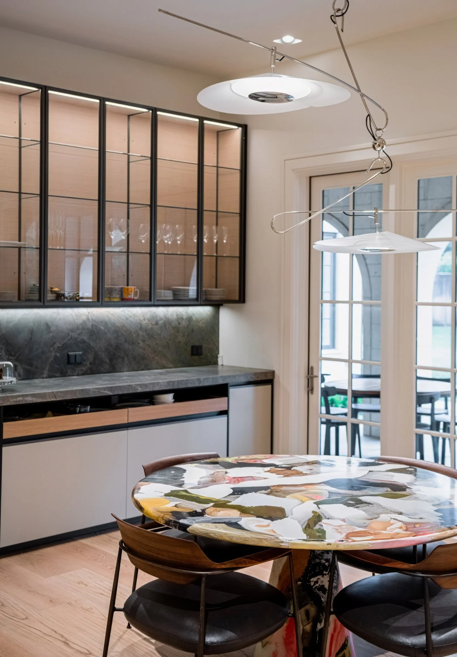 Custom cabinetry, stone surfaces, and a rare collectible Melting Pot dining table define this breakfast room. Layered with architectural lighting by David Weeks and restrained finishes, the space feels both functional and quietly dramatic.