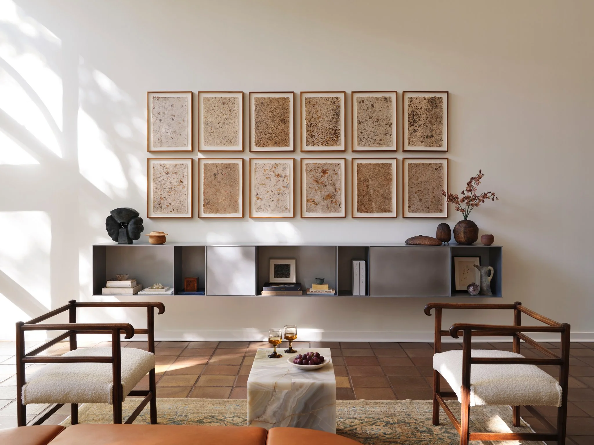 Contemporary shelving by Jonathan Nesci with curated sculptural objects, art, and books, featuring warm light and shadow across minimalist interior architecture.