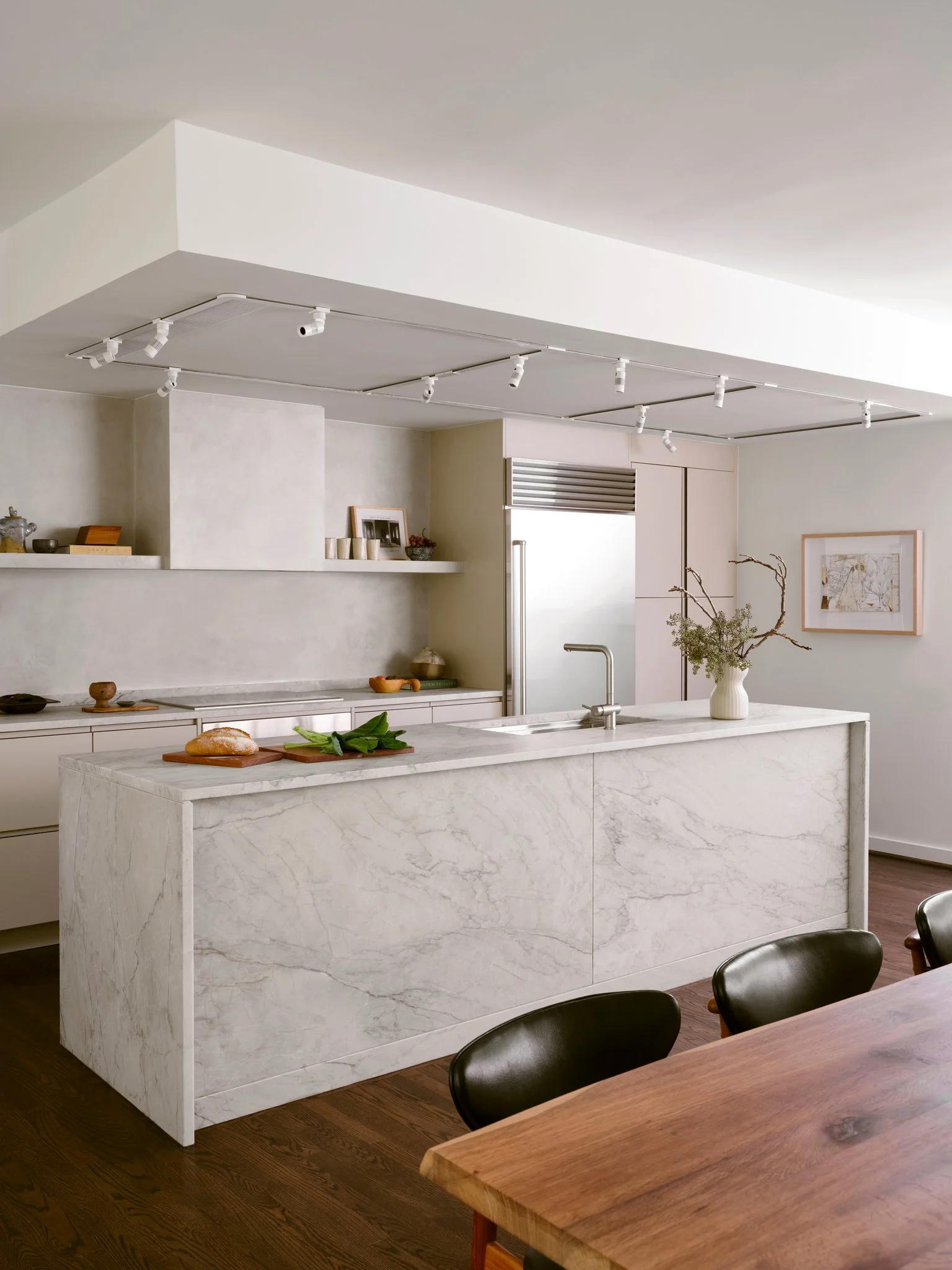 Modern kitchen with Brazilian Quartzite island, plaster walls, and integrated appliances, emphasizing clean lines and material-driven interior design.