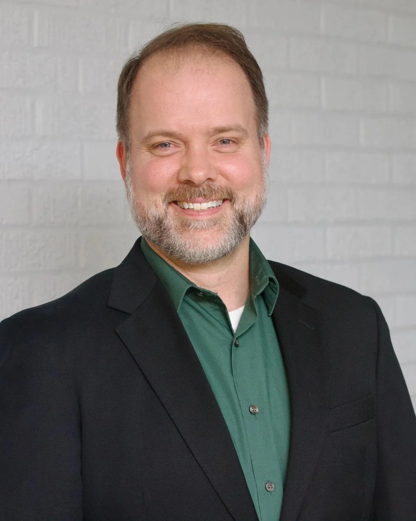 Headshot of District 7 CCSD School Board Candidate Adam Shirley, black coat, deep green shirt
