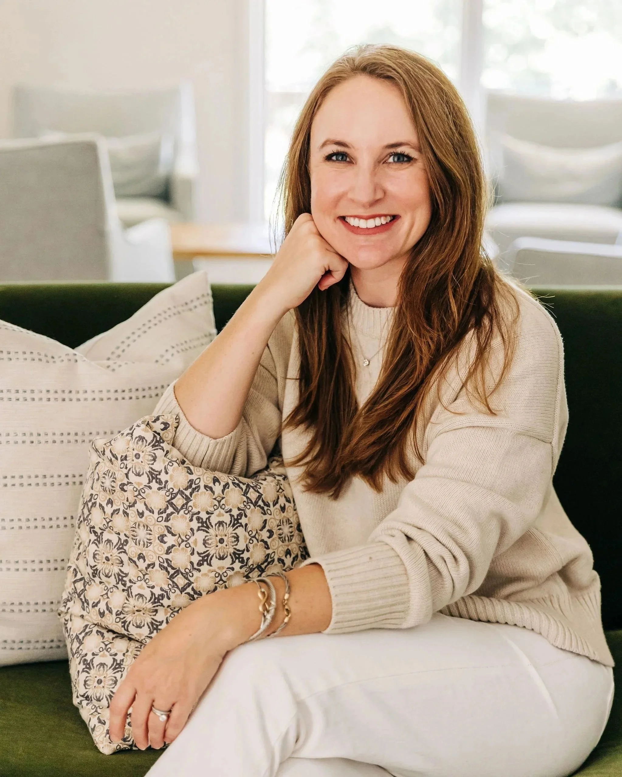 Caroline Dilbeck sitting on a sofa in her home, reflecting on planning and family life.