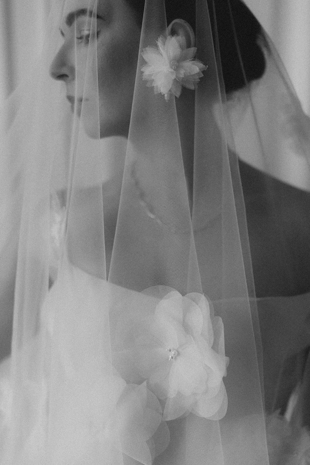 Schwarz-weiß-Fotografie einer Braut mit Schleier und einem Blumenstrauß, seitlicher Profilaufnahme.