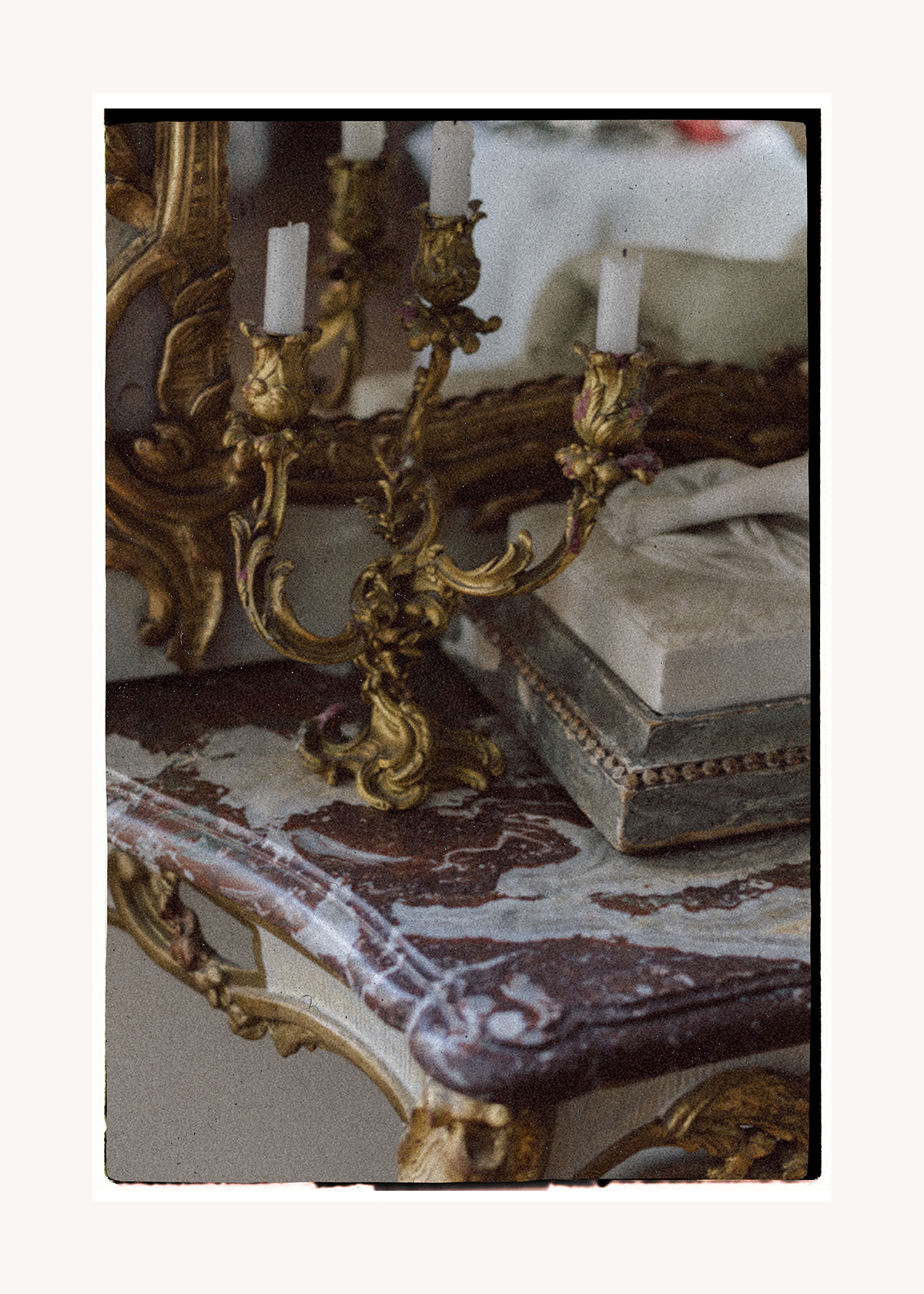 Ein antiker goldener Kronleuchter mit Kerzen steht auf einem Marmortisch.