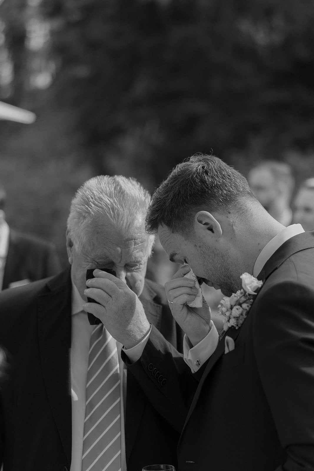 Ein Mann in einem Anzug und eine ältere Frau, wahrscheinlich bei einer emotionalen Zeremonie, bei der sie weinen und sich gegenseitig berühren.