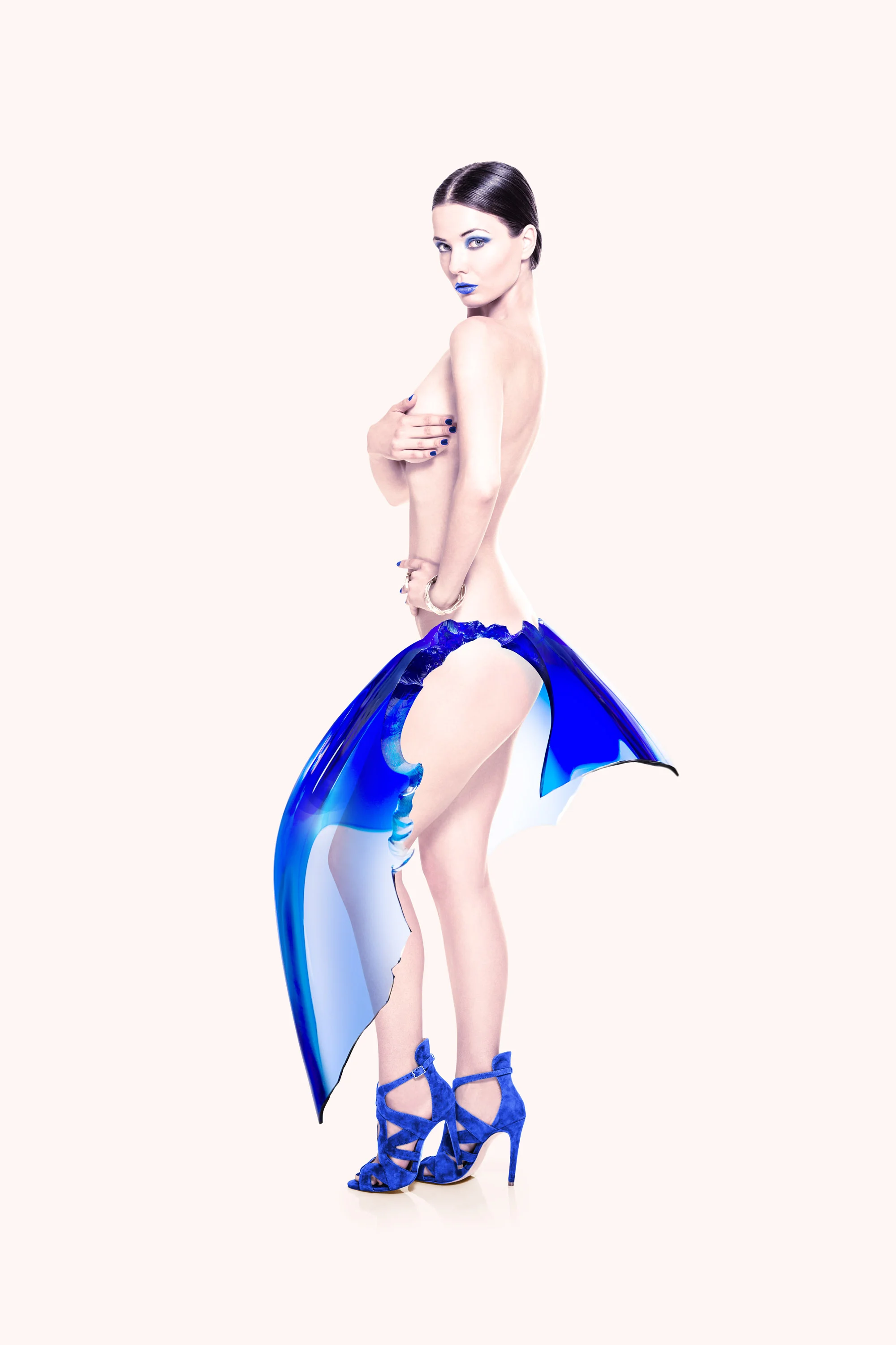 A woman with dark hair and blue makeup, wearing blue high-heeled shoes and a blue tail or skirt, posing against a plain light background.