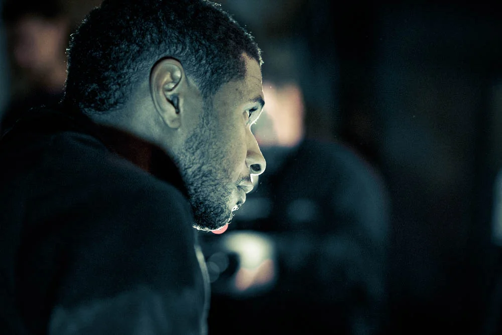 Usher looking intently to the right in his dimly lit recording studio.