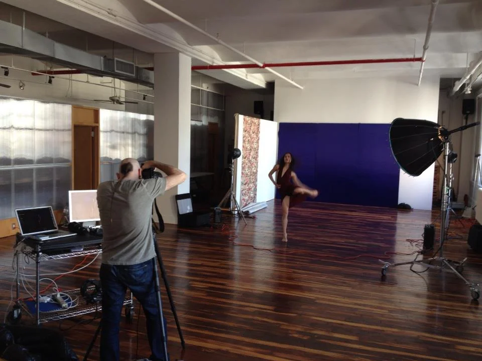 A photographer taking pictures of a dancer in a studio with professional lighting and backdrops.