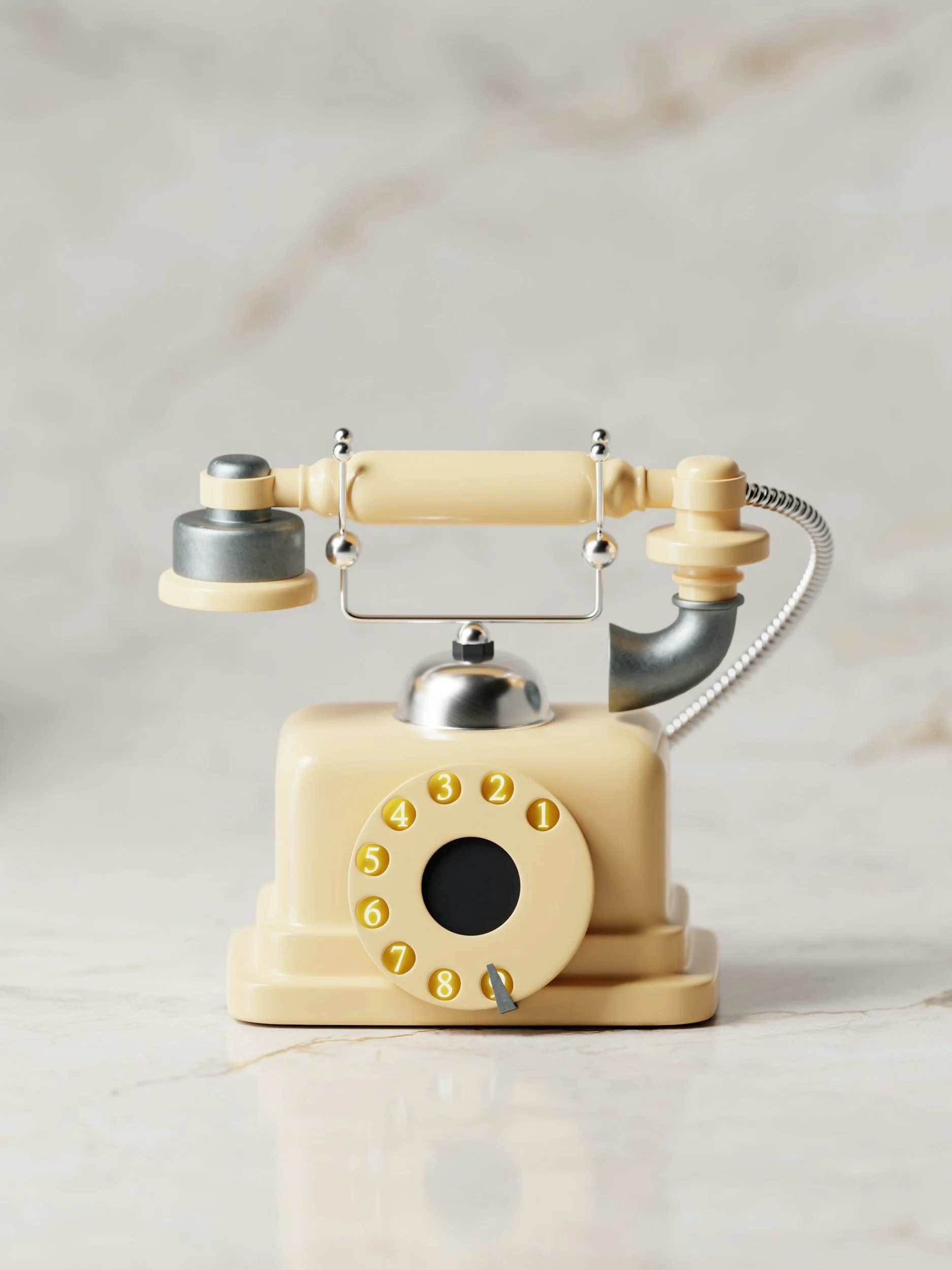 Vintage rotary telephone with a beige and silver design on a marble surface.