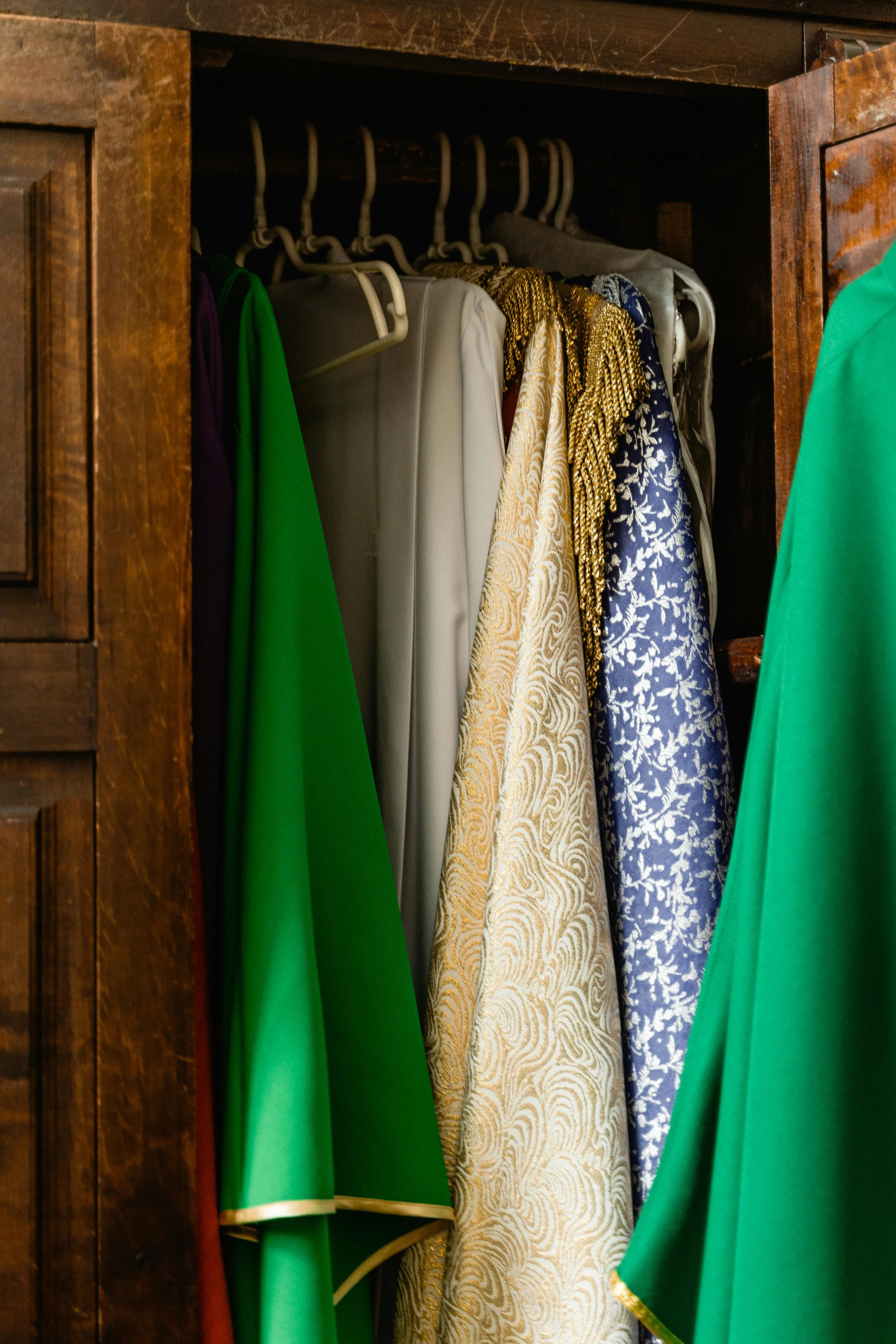 A personal stylist conducting a wardrobe edit featuring a rail full of beautiful clothes in rich colours and sumptuous fabrics