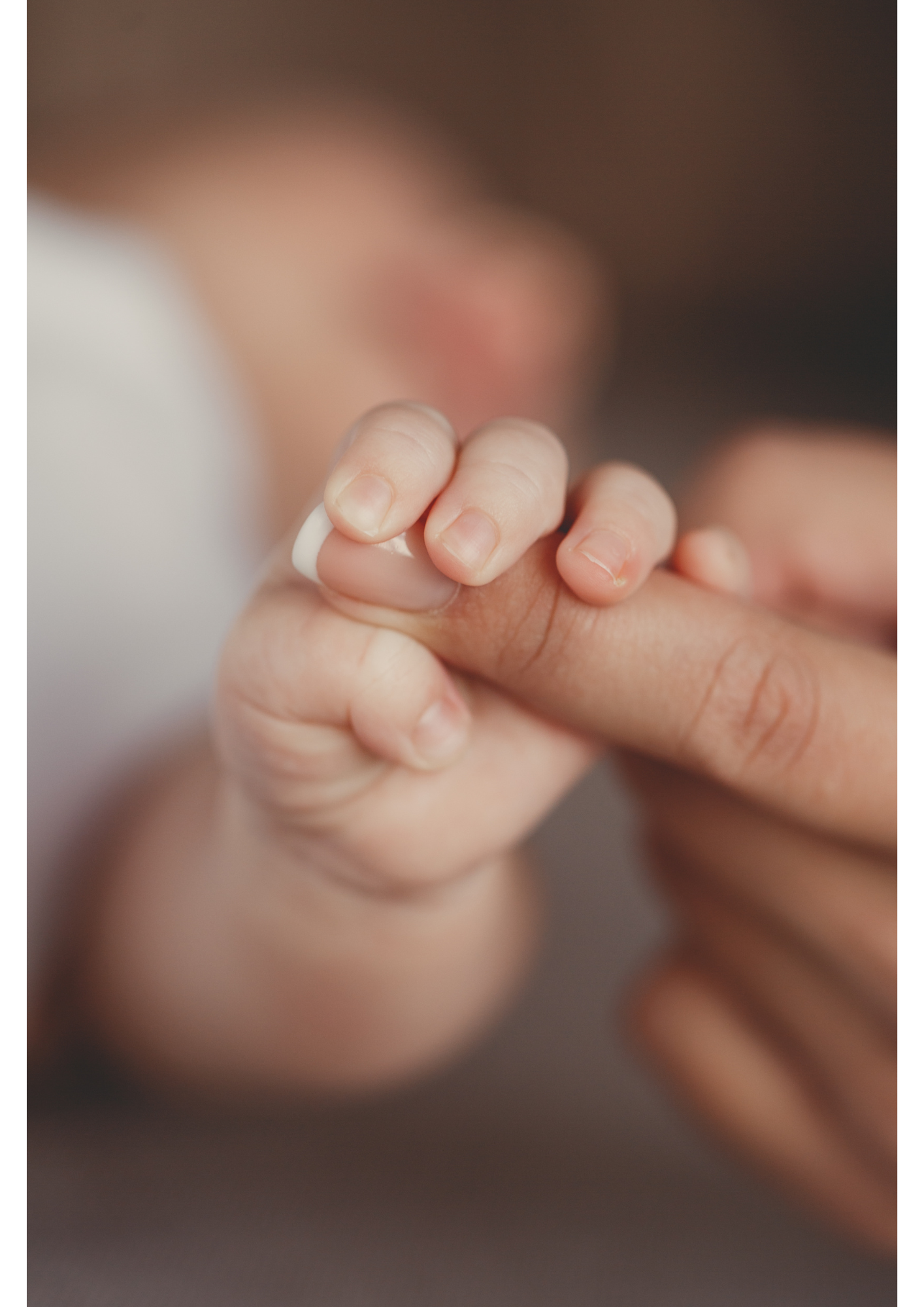 Une main de bébé tenant le doigt d'un adulte.