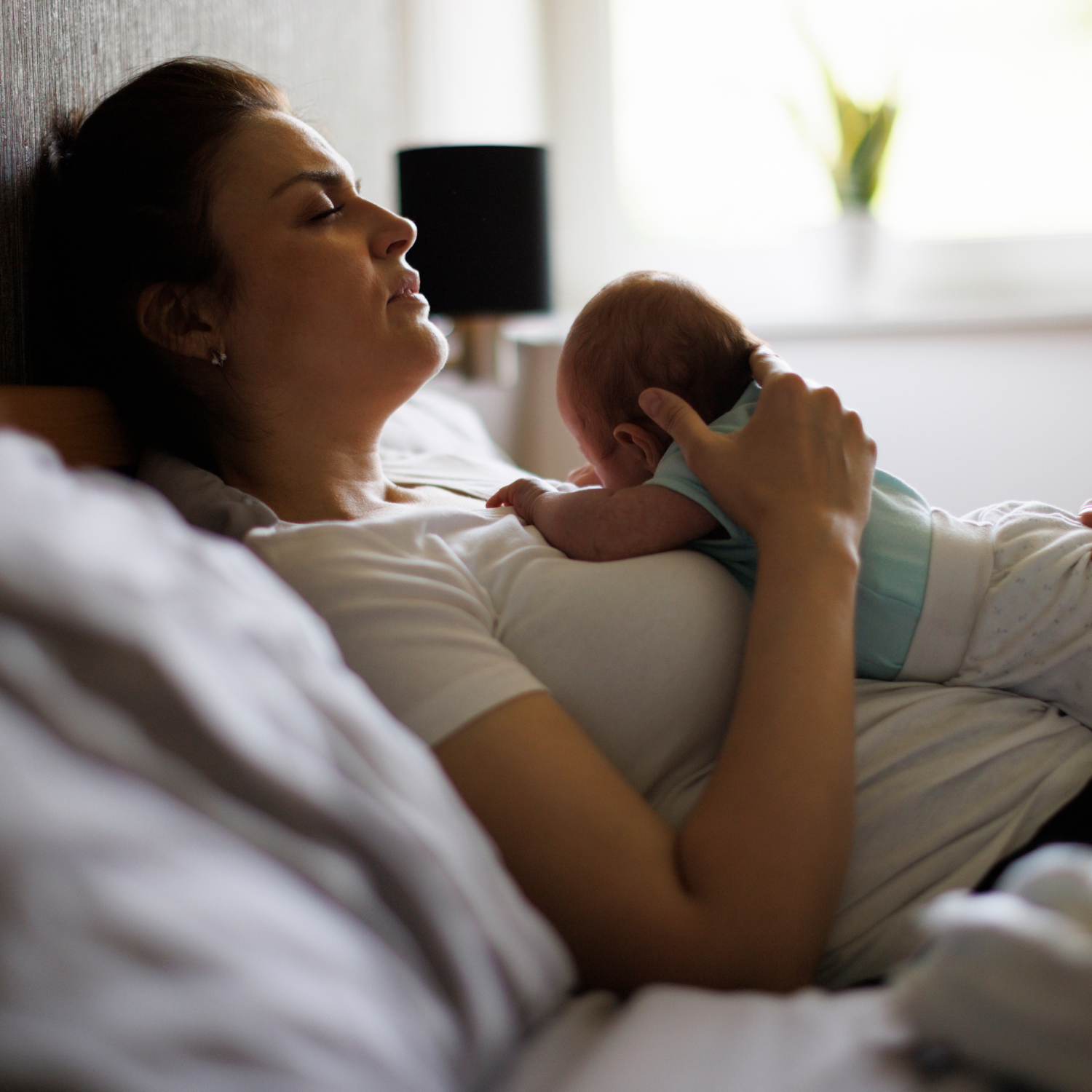Mère en post-partum allongée avec son nouveau né sur le ventre, visiblement très fatiguée