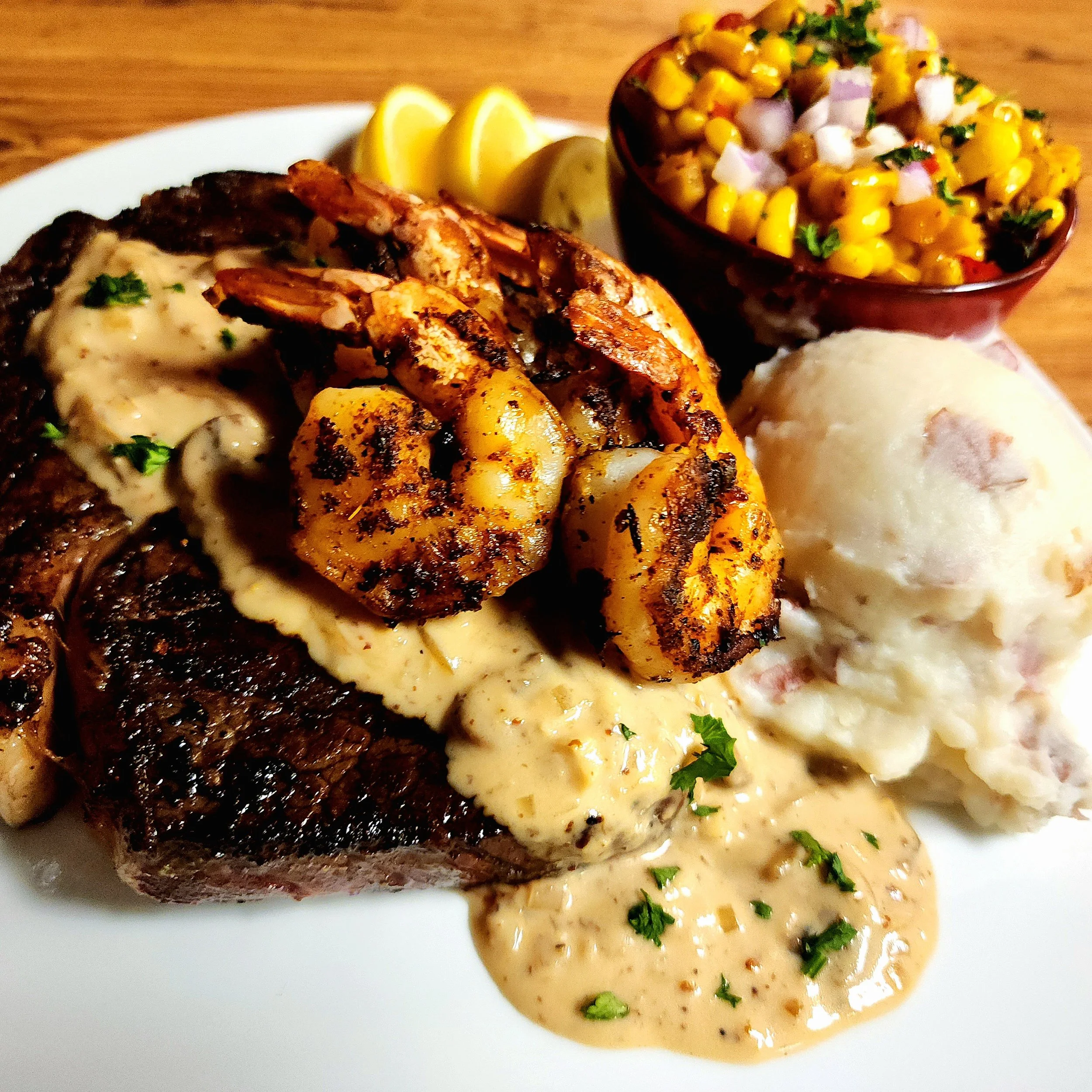 14oz Pan Seared Ribeye with Blackened Gulf Shrimp & a Cognac Creole Cream Sauce.