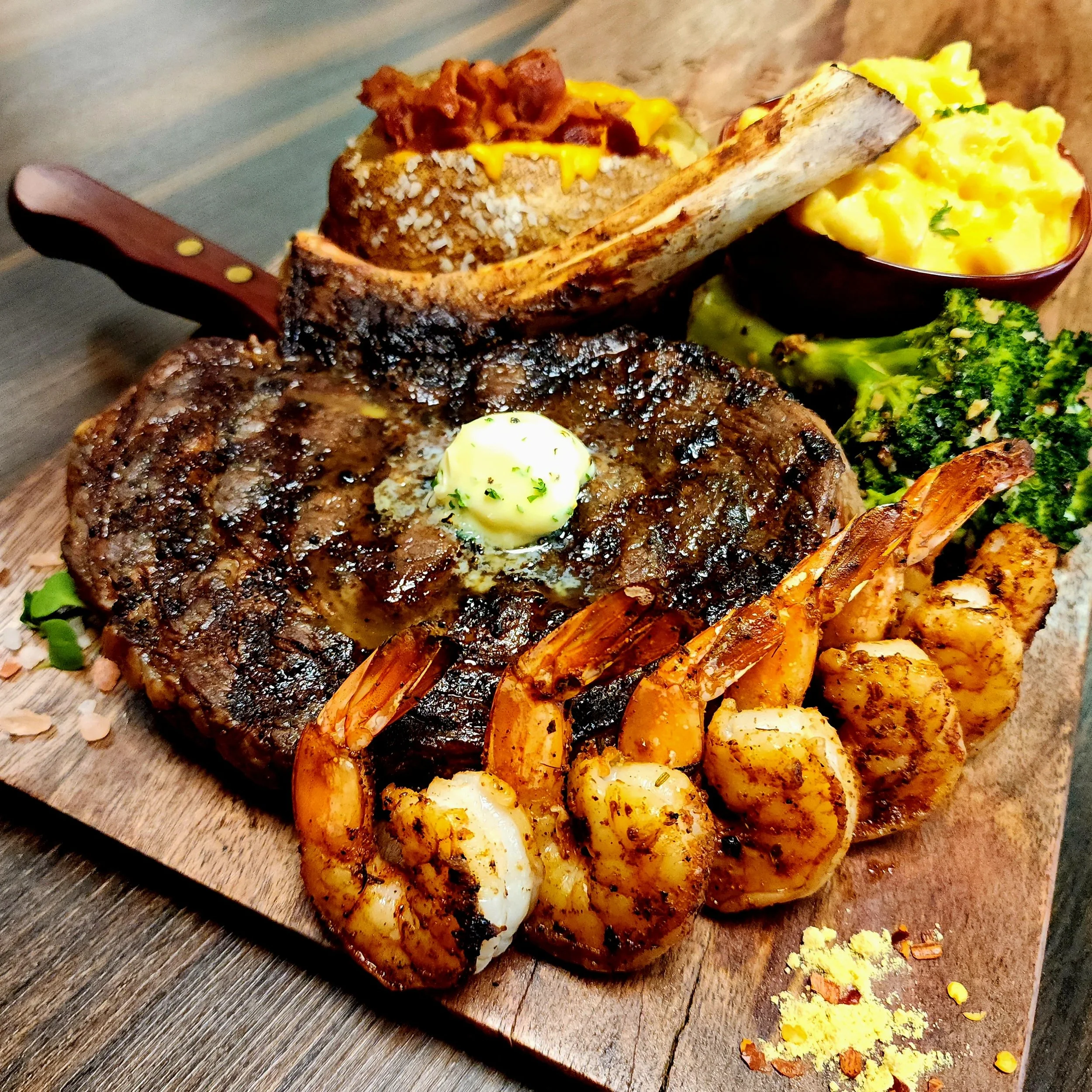 28oz Bone-In Campfire Cowboy with Blackened Gulf Shrimp, Loaded Baked Potato, & Scratch Made Mac n' Cheese.