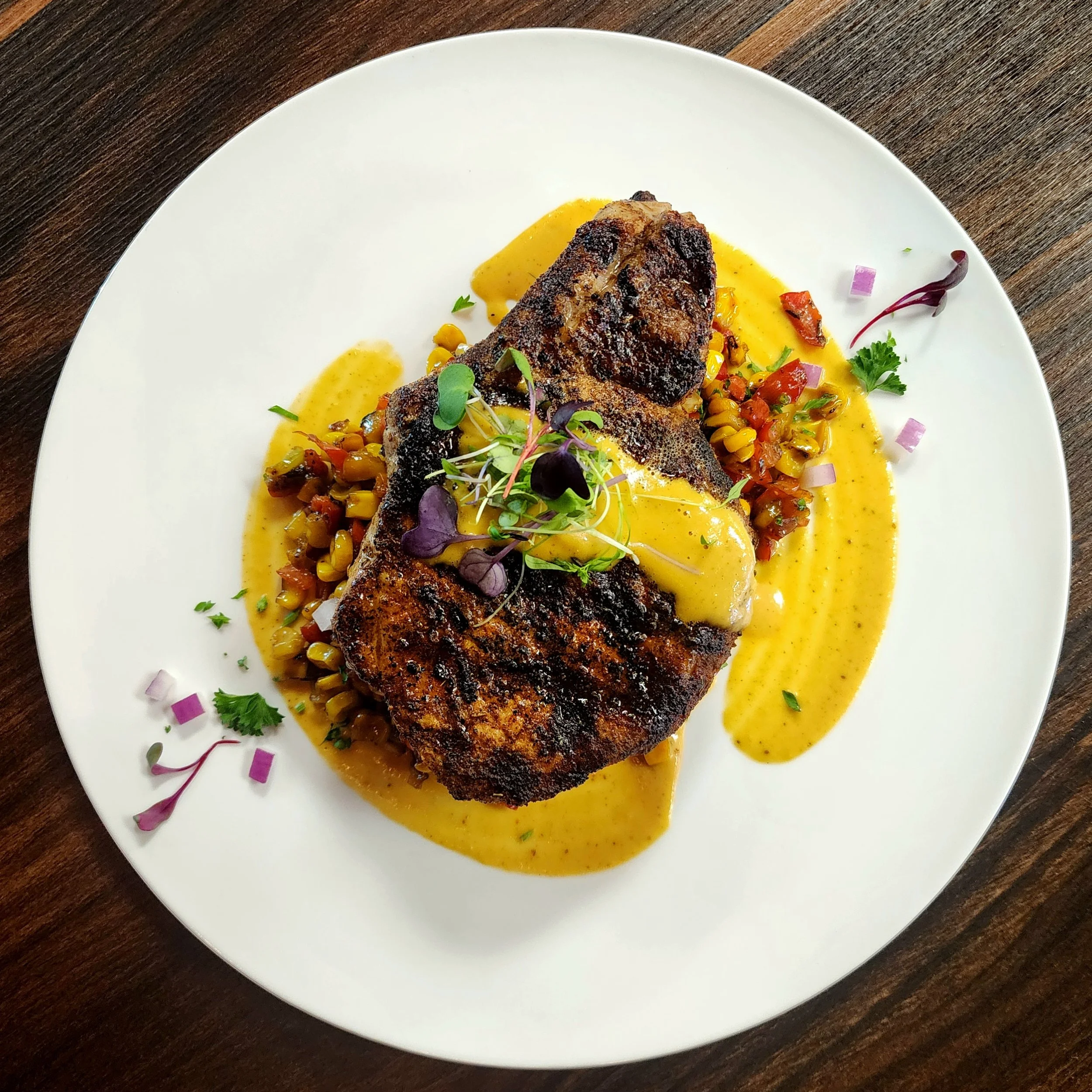 Blackened Dry-Aged Bone-In Pork Chop with Maque Choux & a Creole Corn Puree. 