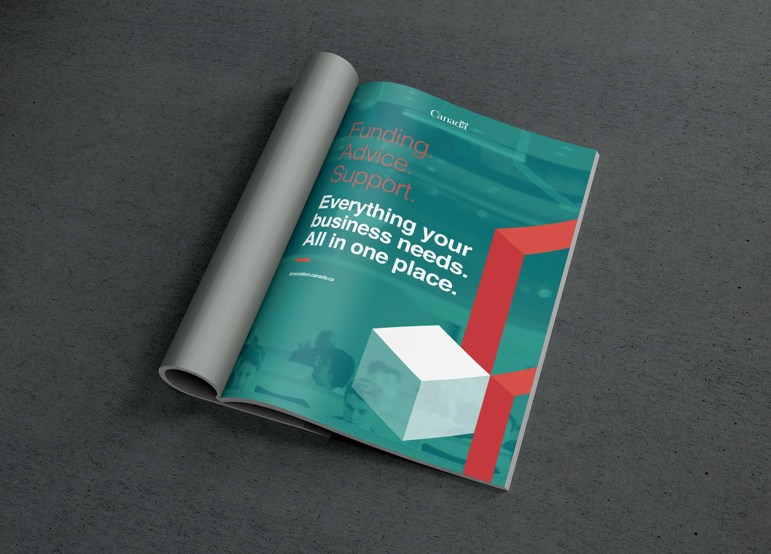 Open magazine on a dark surface showcasing a Canadian business support guide with a teal background, red and white graphics, and the text 'Funding. Advice. Support. Everything your business needs. All in one place.'