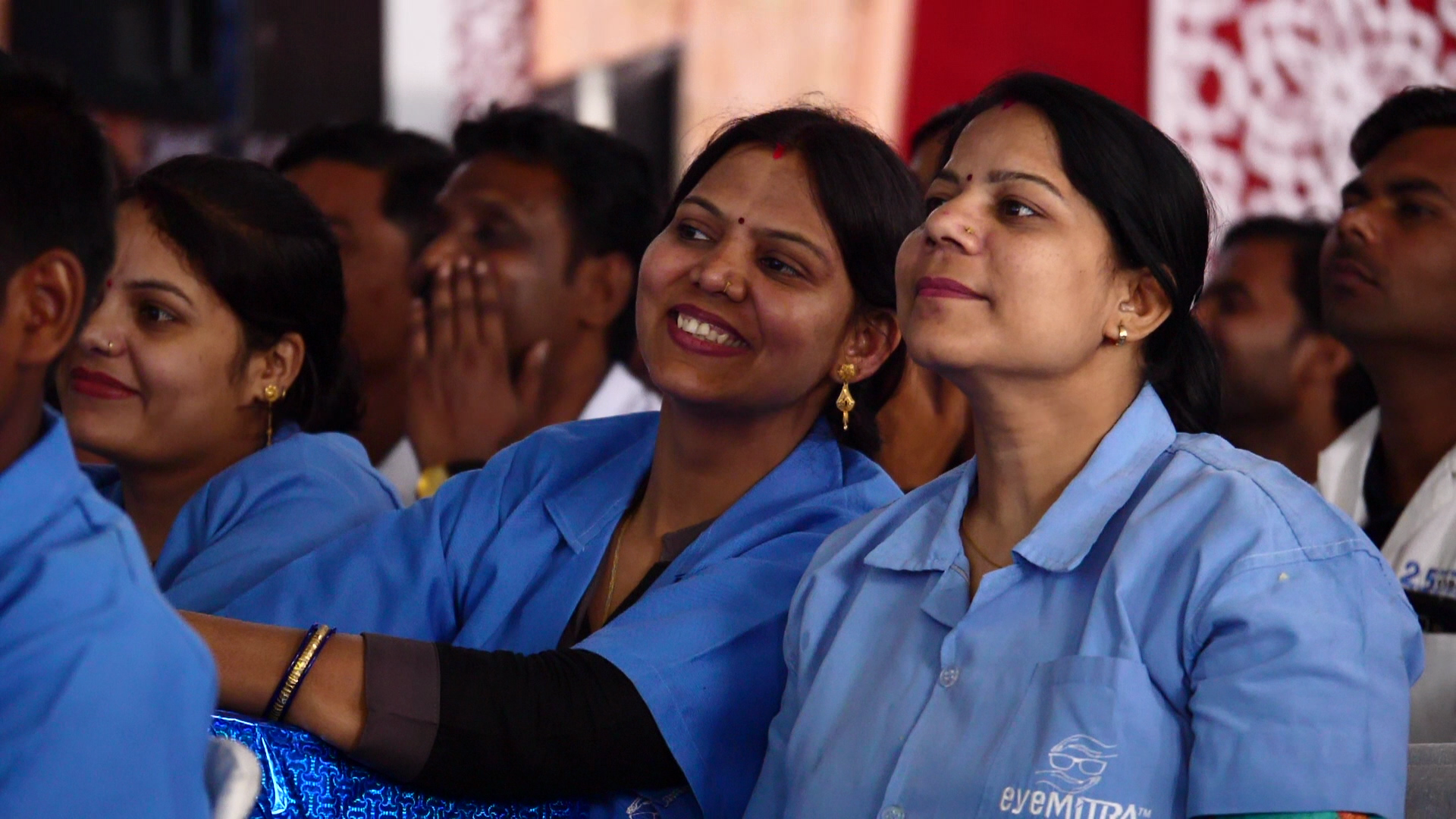 Group of women in blue shirts attending an event, smiling and engaged.