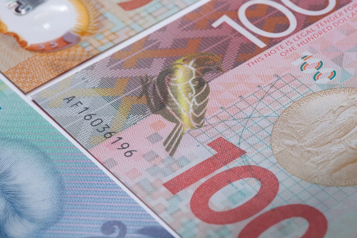 Close-up of Australian currency notes, showcasing a red $100 note and parts of other notes with colorful designs and security features.