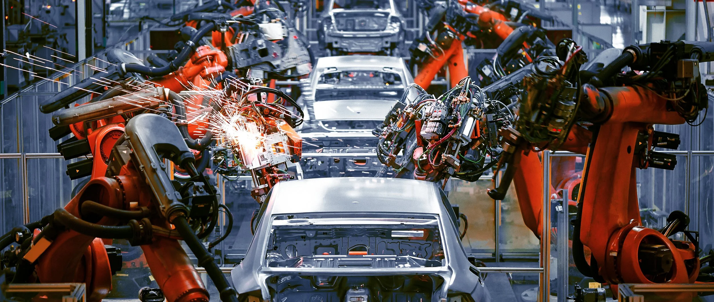 Robots assemble car bodies on a manufacturing line in an auto factory.