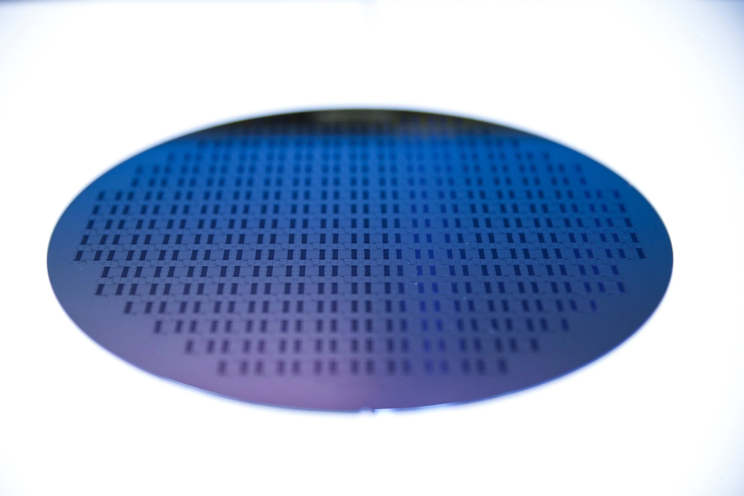 Close-up of a computer microprocessor or integrated circuit with a grid-like pattern of small rectangles, with a bright light background.