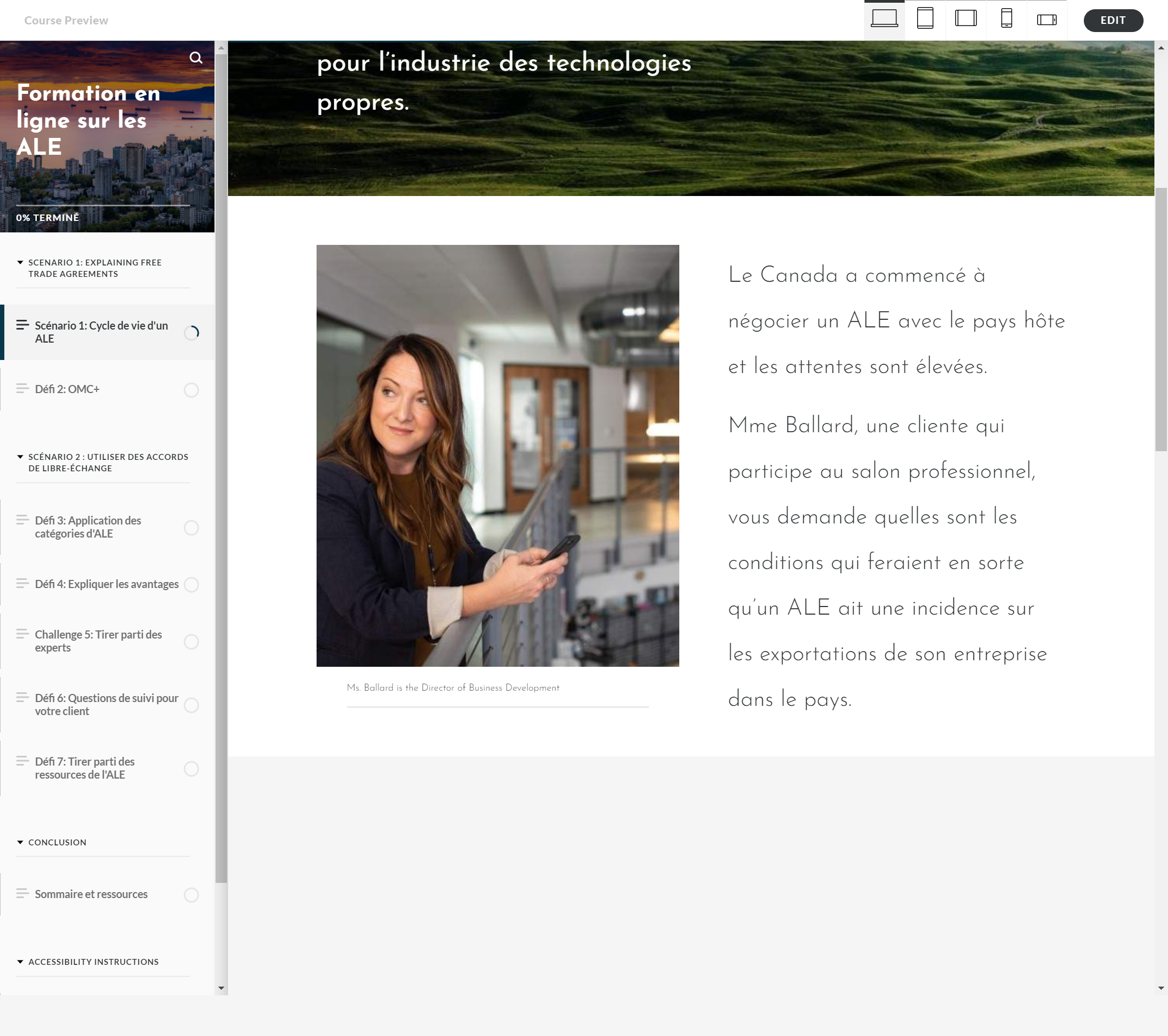 A woman with brown hair holding a smartphone, standing on a balcony railing in an office building.