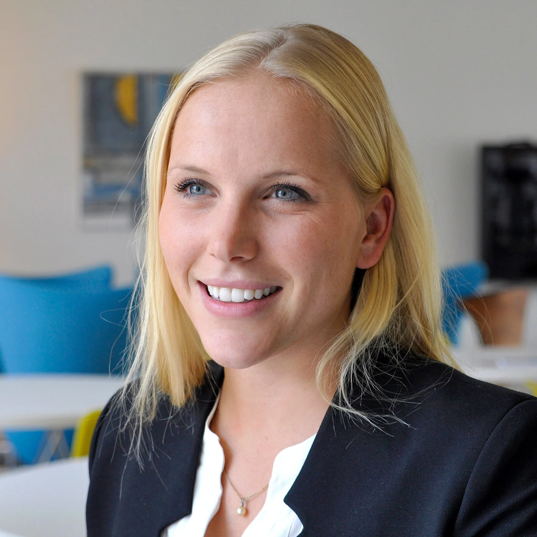 Lächelnde blonde Frau, die formelle Kleidung trägt, im Büro.