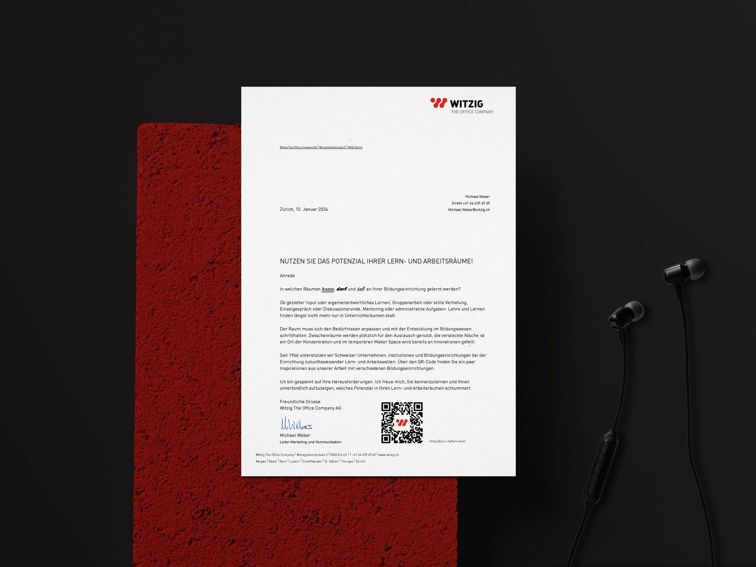 Ein Brief von Witzig The Office Company, mit schwarzem Hintergrund, rote Textur auf der linken Seite und schwarze Ohrhörer auf der rechten Seite.