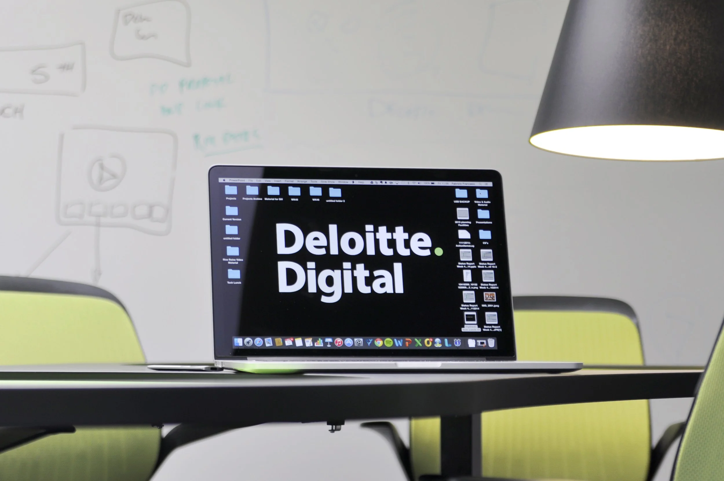 Ein Laptop auf einem Tisch, der den Schriftzug auf dem Bildschirm zeigt, unter einer schwarzen Deckenleuchte in einem modernen Büro.
